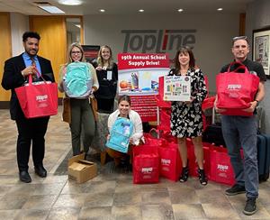 TopLine employees stand with nonprofit partners with school supply donations.