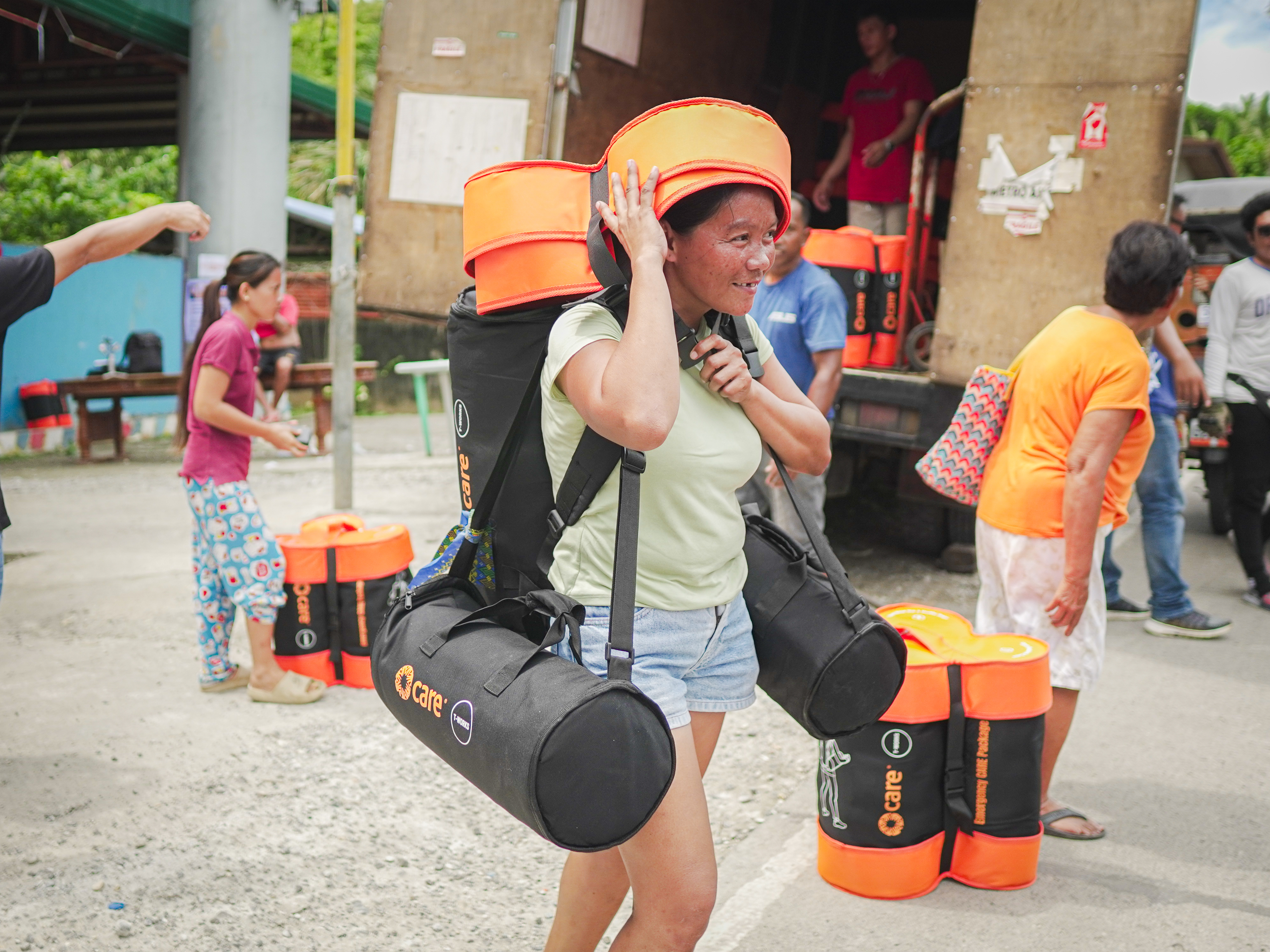 A woman in Cebu Province in the Philippines collects a CARE PACKAGE kit for her family at a distribution site set up after an earthquake in October 2025. The Philippines was among the countries where the new CARE PACKAGE for Emergencies was piloted. Credit: Zhynnon Mar Mantos/CARE