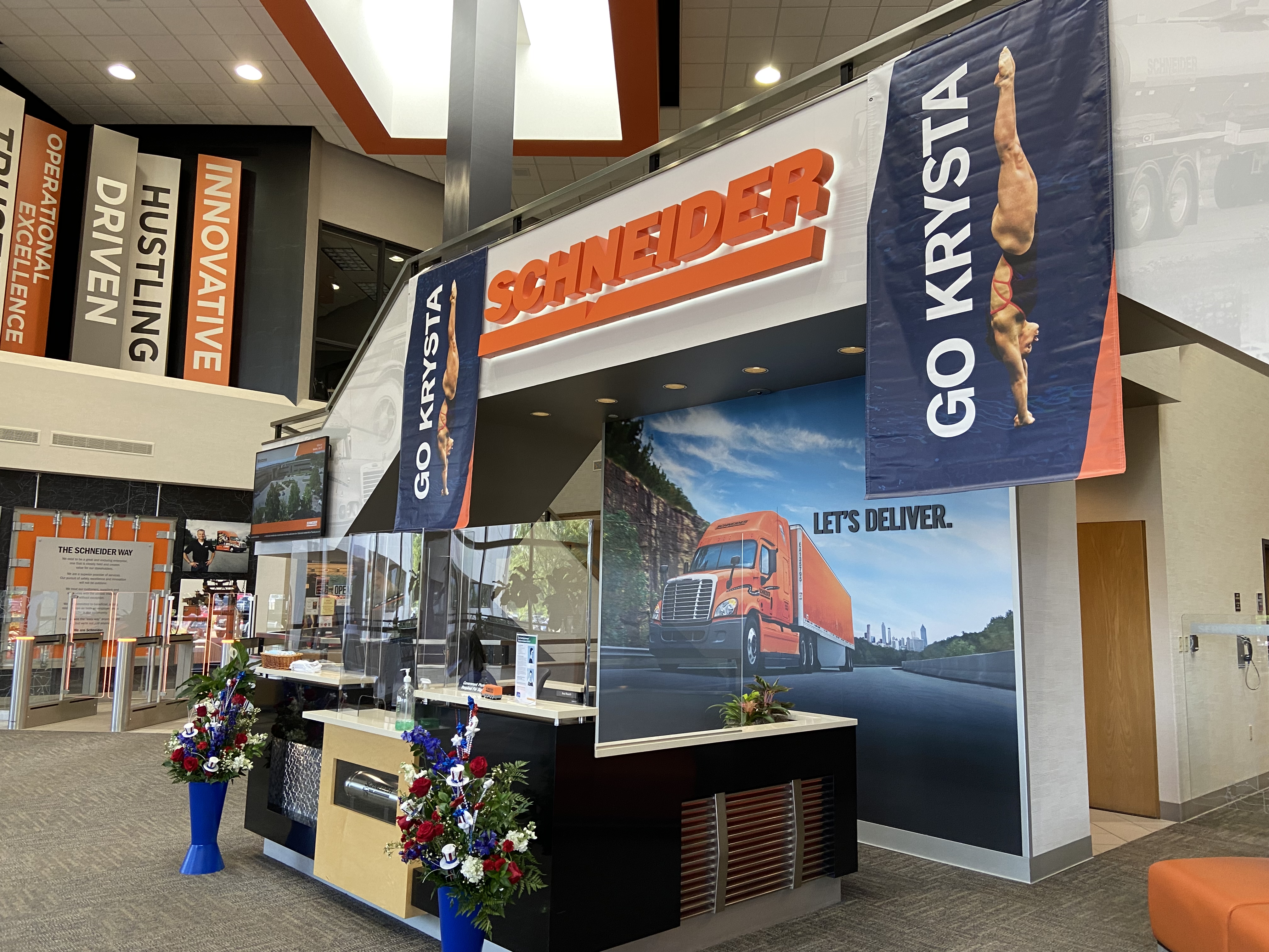 Schneider rallies behind USA diver Krysta Palmer. Photo of Go Krysta banners in the lobby of Schneider's Green Bay headquarters. 