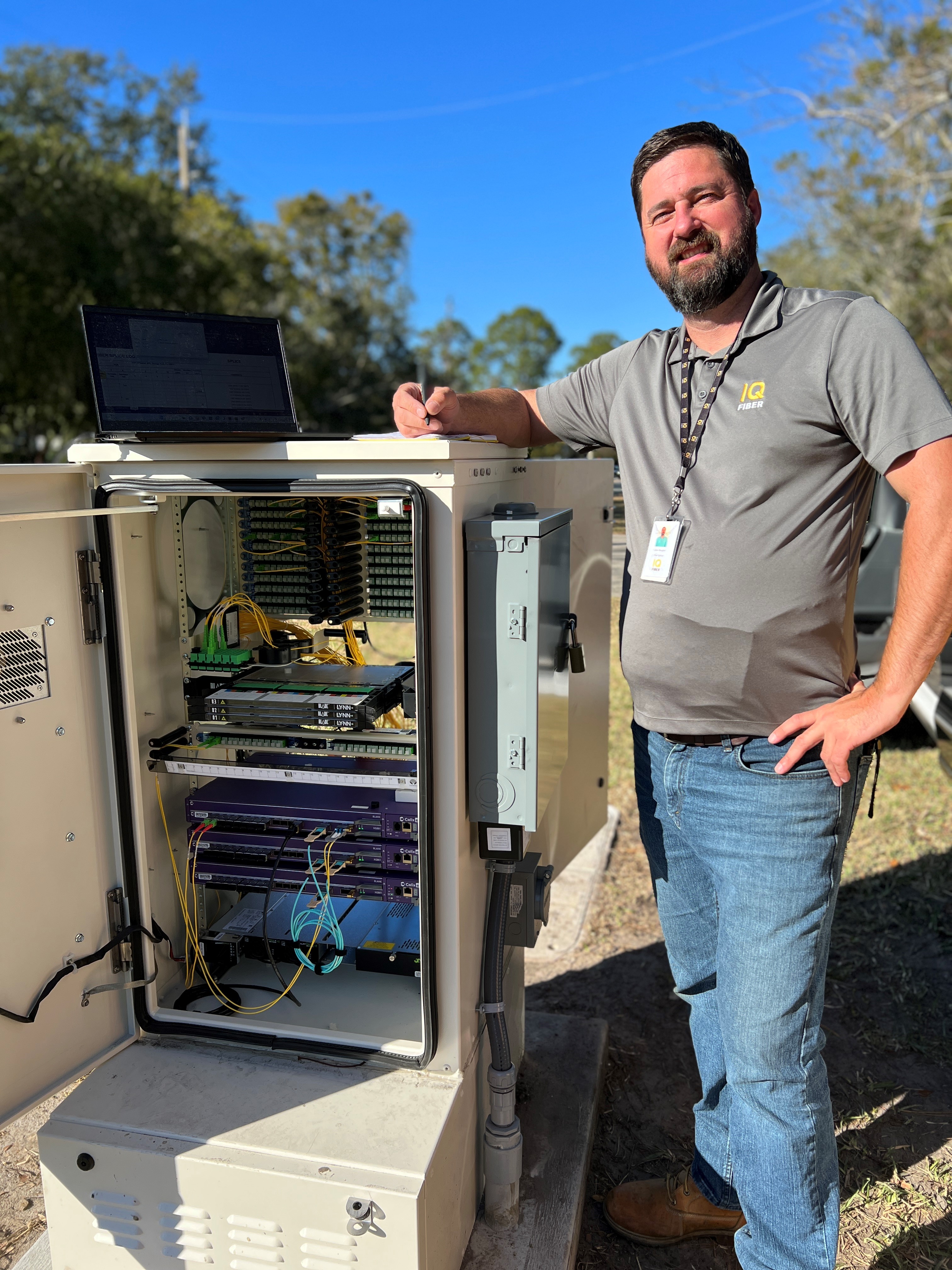 IQ Fiber engineer Jason Baugher (pictured) stands with a fiber-optic cabinet. These metal boxes protect fiber-optic cables from the elements and provide easy access for maintenance and upgrades.