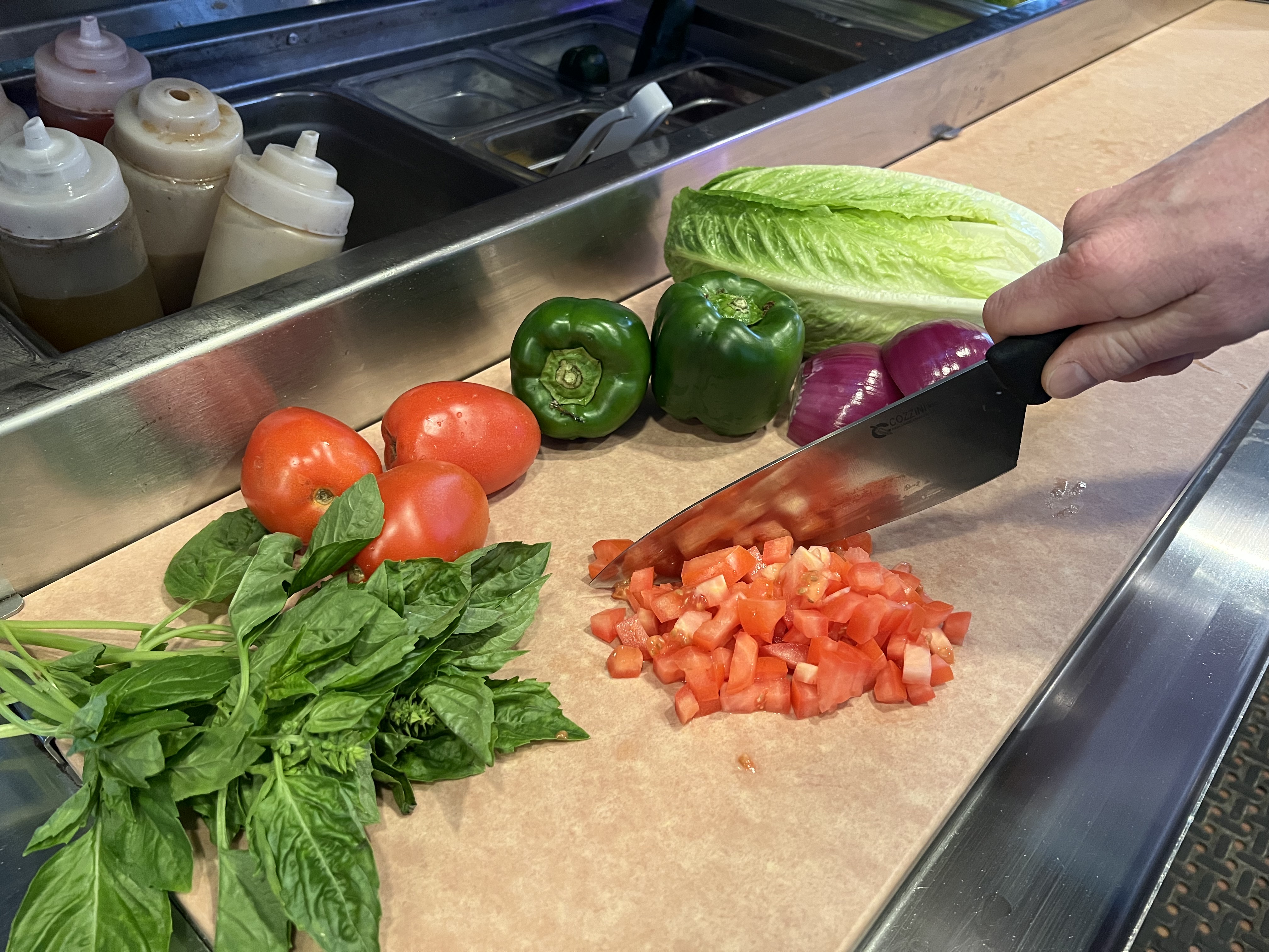 Fresh vegetables being cut on Richlite culinary surface.