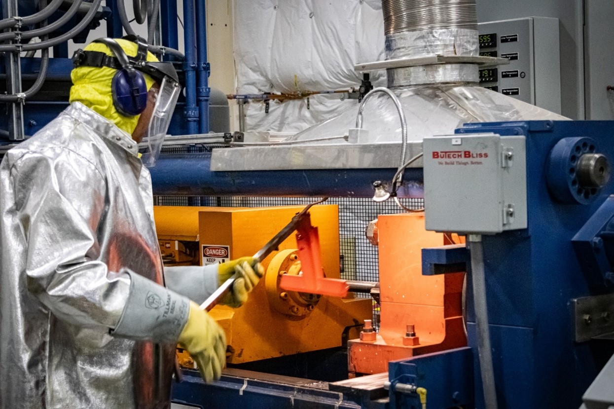 Heated-up billet assembly being loaded into the extrusion press prior to co-extrusion