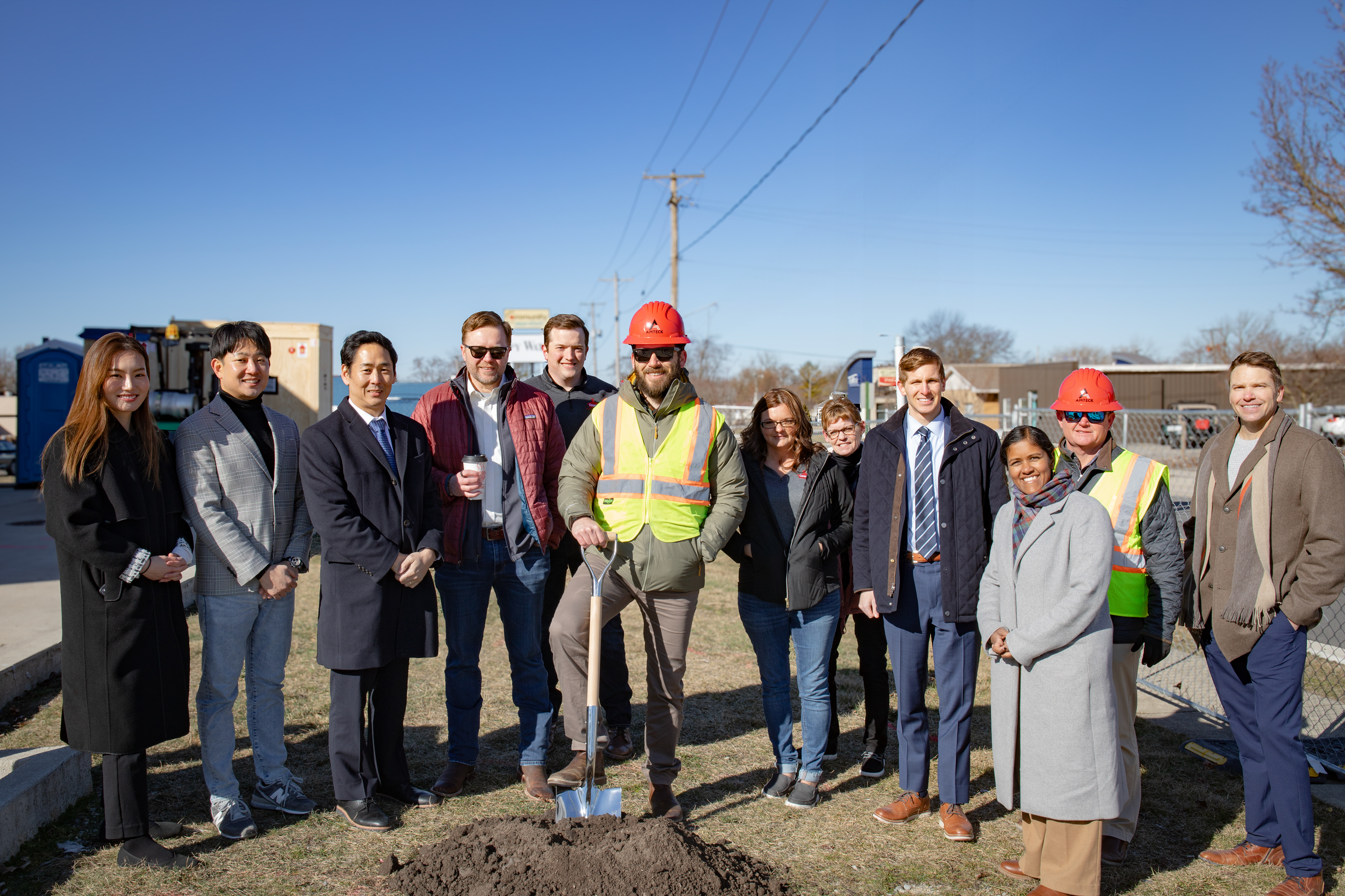 People post with shovels on site of ground breaking