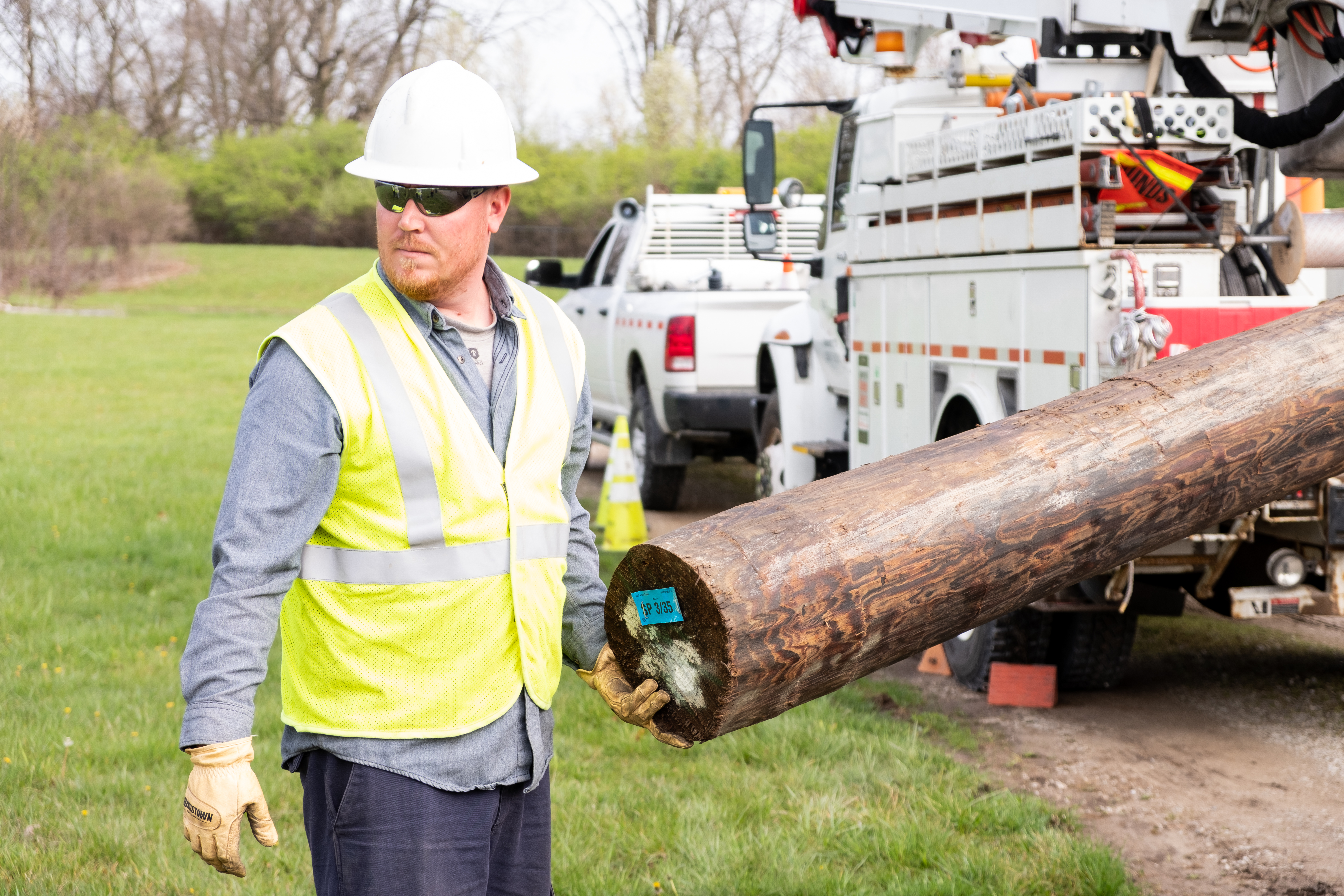 Lineman guides new pole into position for installation. 