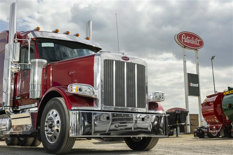 Gros plan de l'avant d'un camion Peterbilt avec de grands panneaux Brandt et Peterbilt derrière.