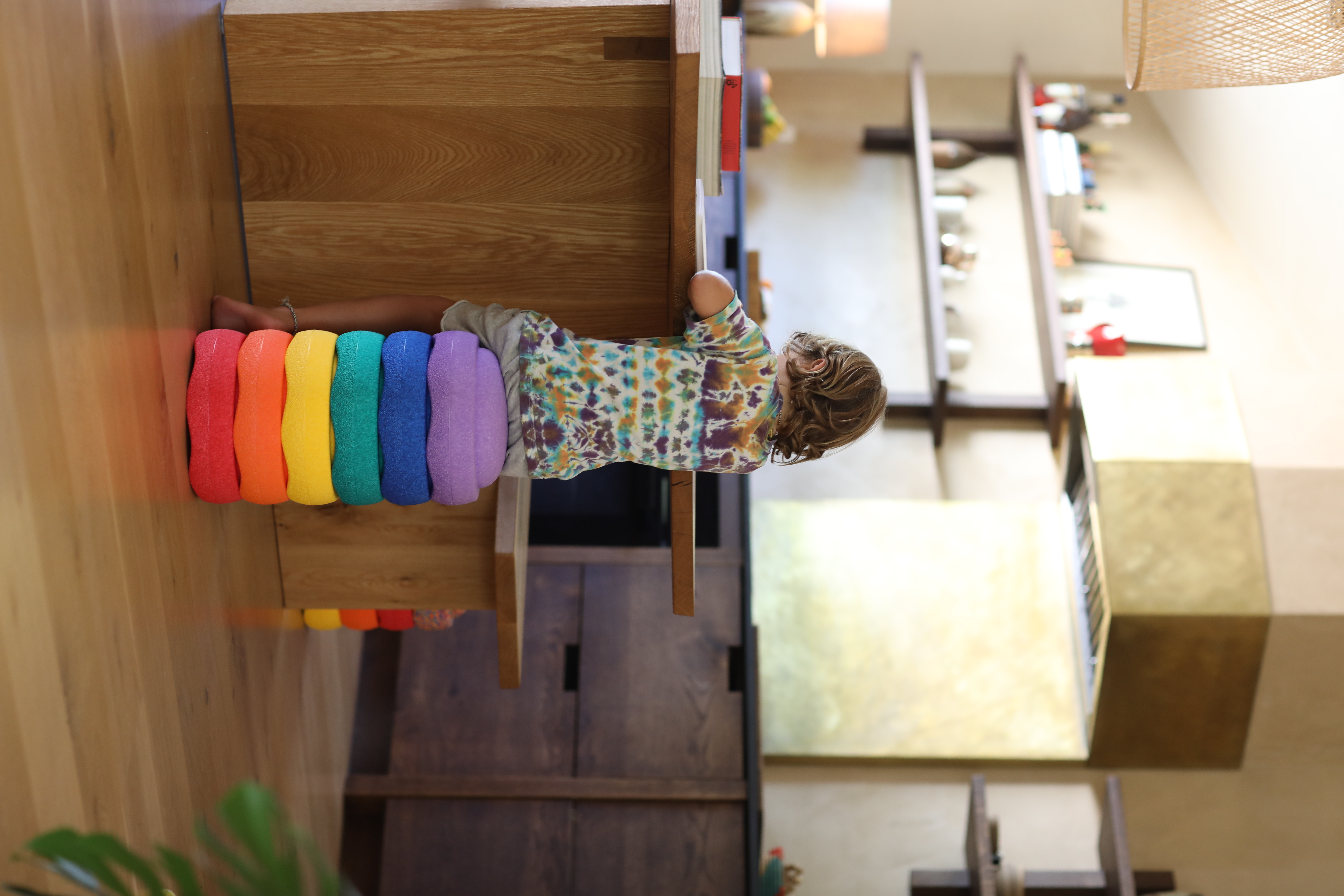 Image shows a child sitting on a stack of Stapelstein elements like a stool at the counter