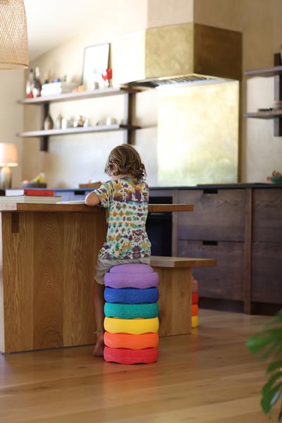 Image shows a child sitting on a stack of Stapelstein elements like a stool at the counter