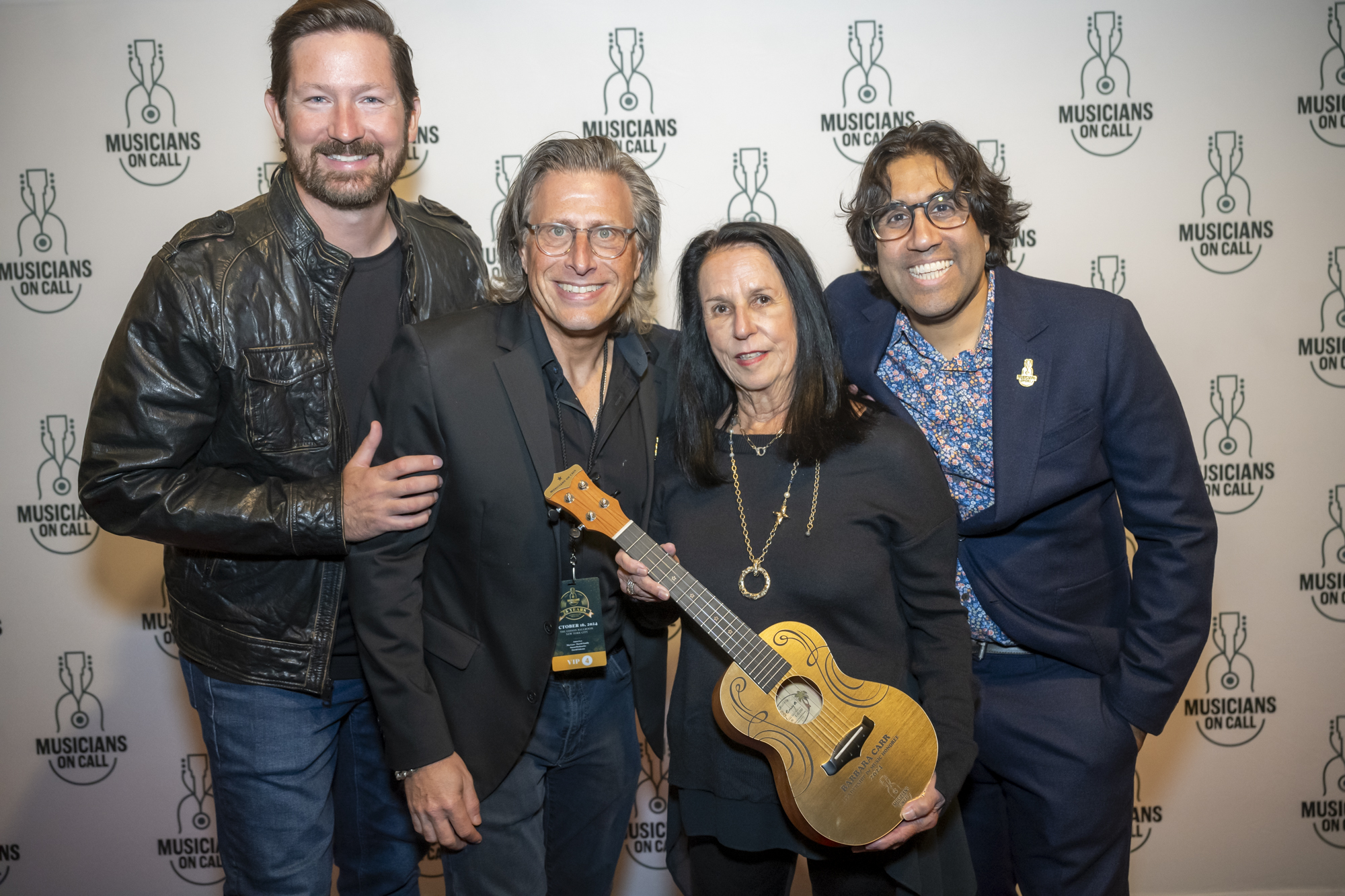 Musicians On Call President & CEO Pete Griffin, Co-founders Michael Solomon and Vivek J. Tiwary post with Barbara Carr and her Leadership in Music Golden Ukulele on the red carpet of MOC's 