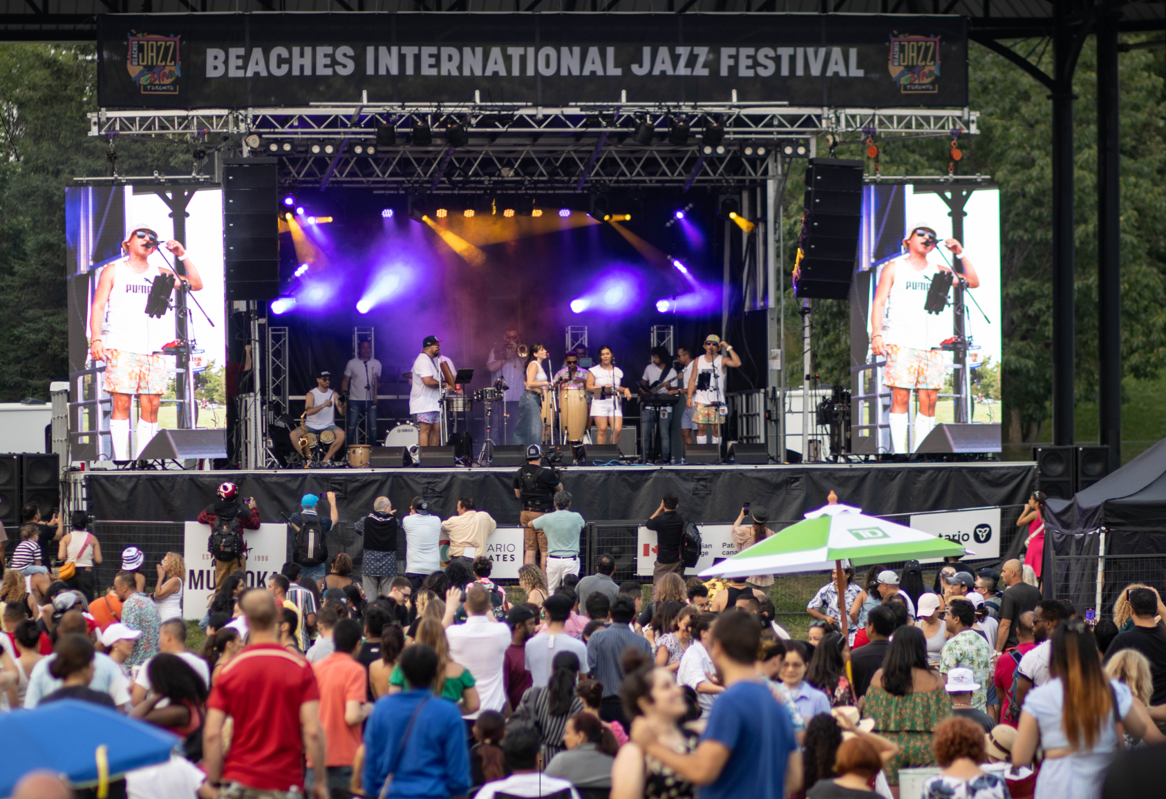 Latin band playing on stage with crowd in front of stage at Toronto's Beaches International Jazz Festival.