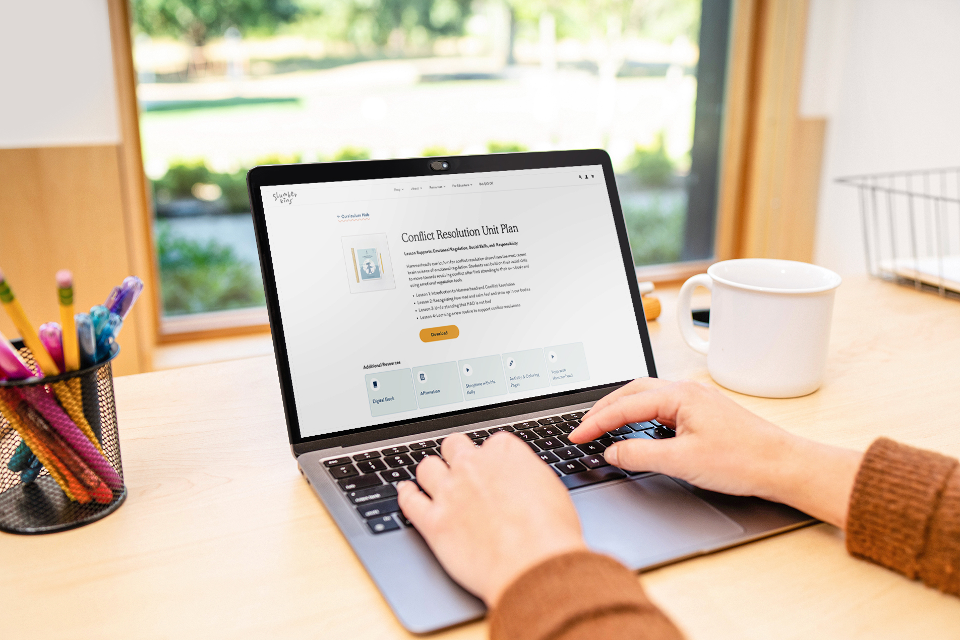 An educator's hands are visible on the keyboard of a laptop as they access a unit plan on the Curriculum Hub website