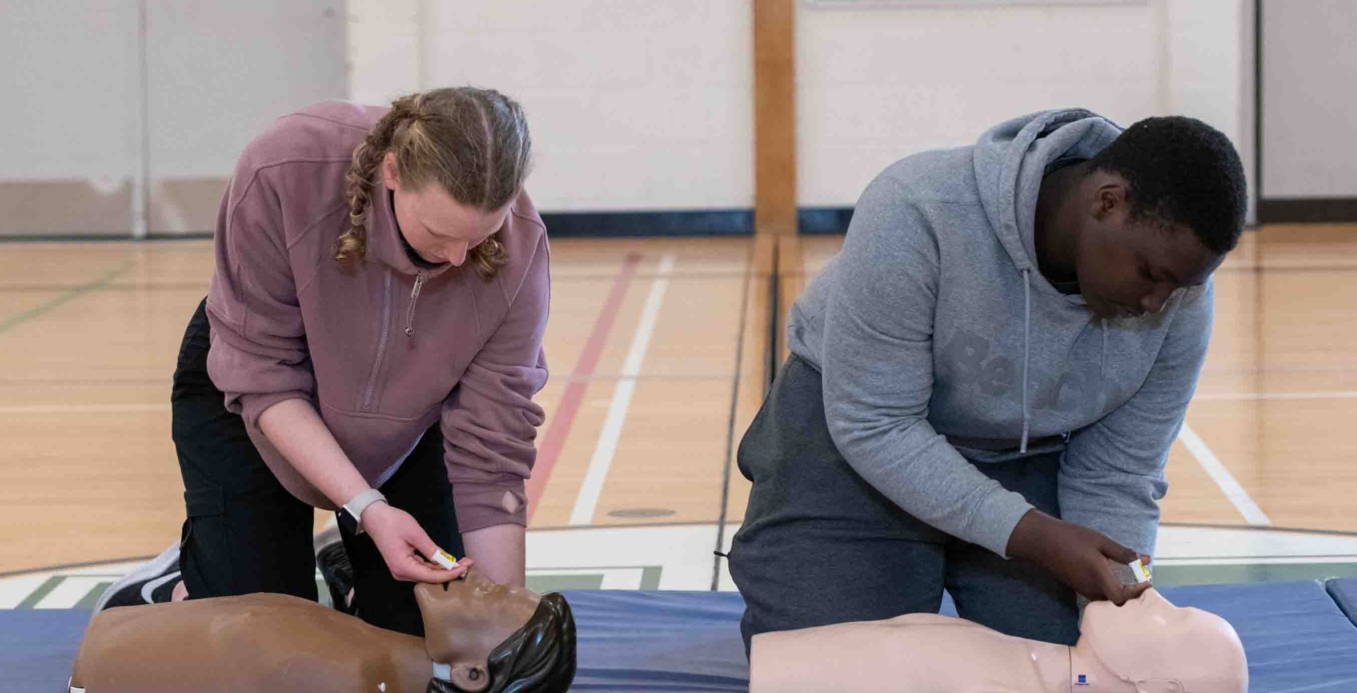 Two students demonstrate how to administer nasal Naloxone on CPR mannequins, as part of the Opioid Overdose Response Training enhancement to the ACT High School CPR and AED Program.