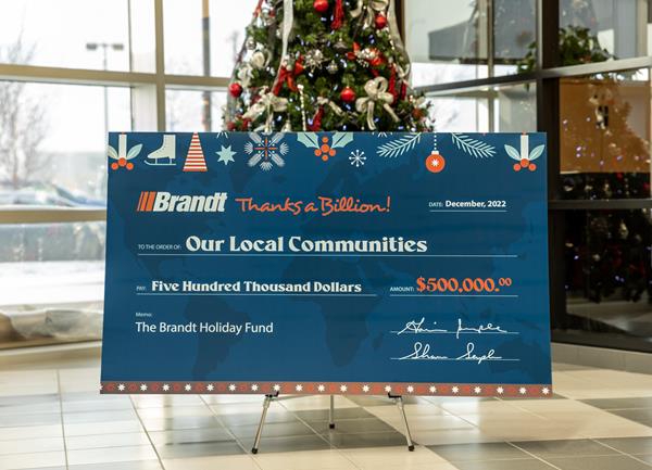 Photo of a large donation cheque in front of a Christmas tree.