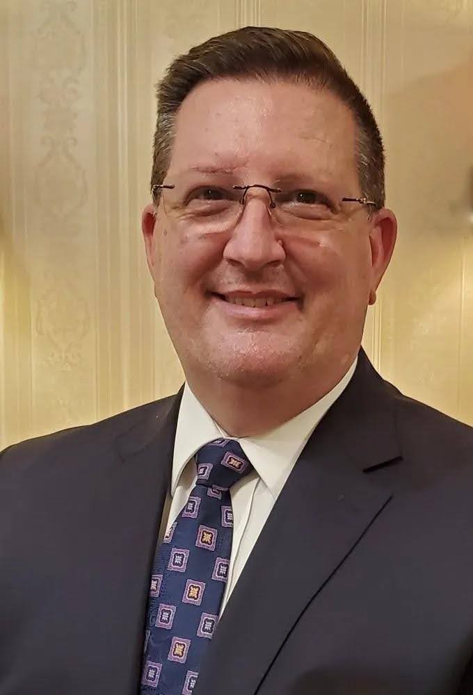 Darren L. Parker, in a dark suit, white shirt, and tie is the Owner, Manager, and Licensed Funeral Director of McDougal Funeral Homes in Taylorsville