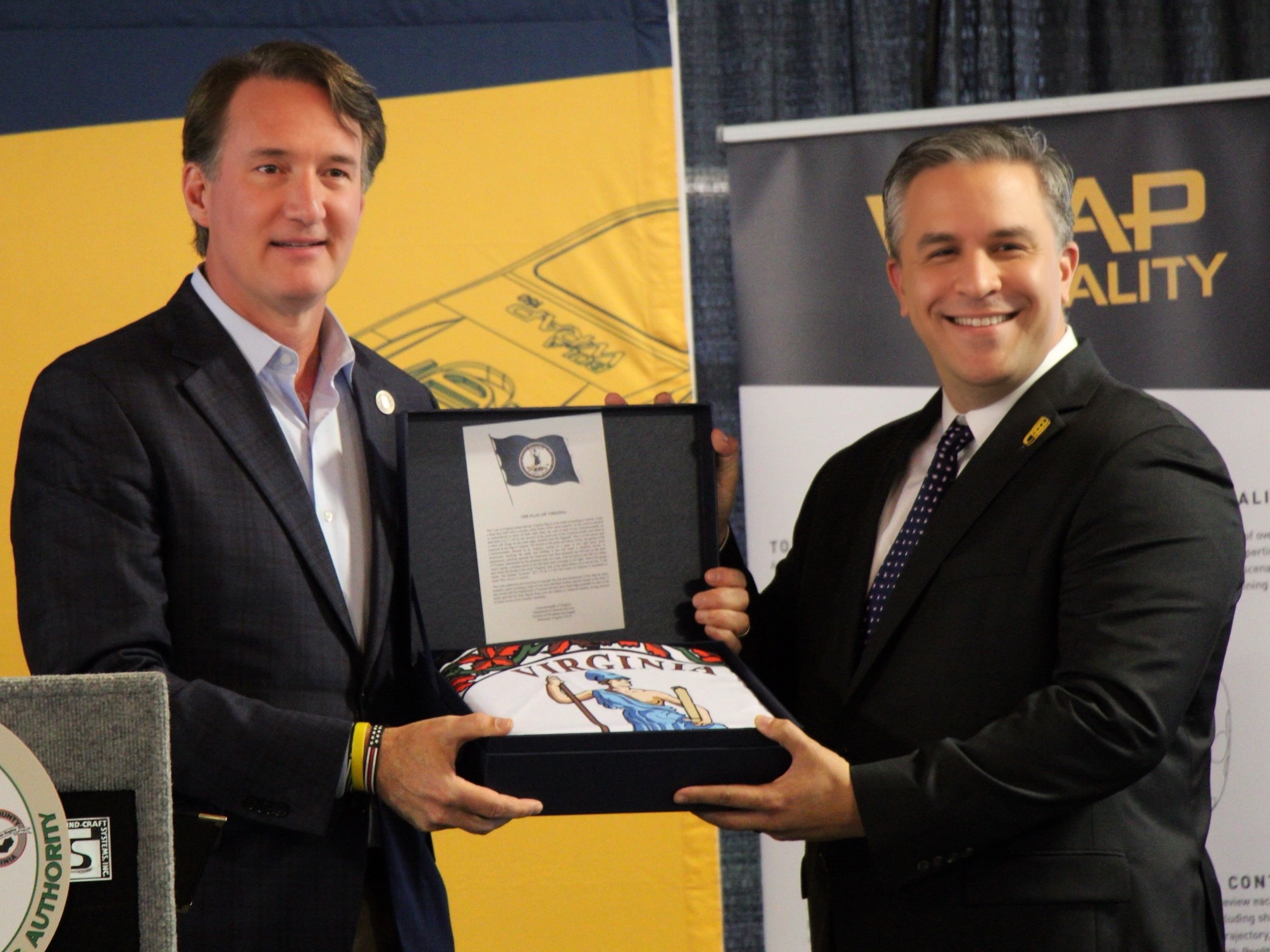 Photo of Governor Youngkin Presenting a Virginia State flag to Wrap COO Jared Novick