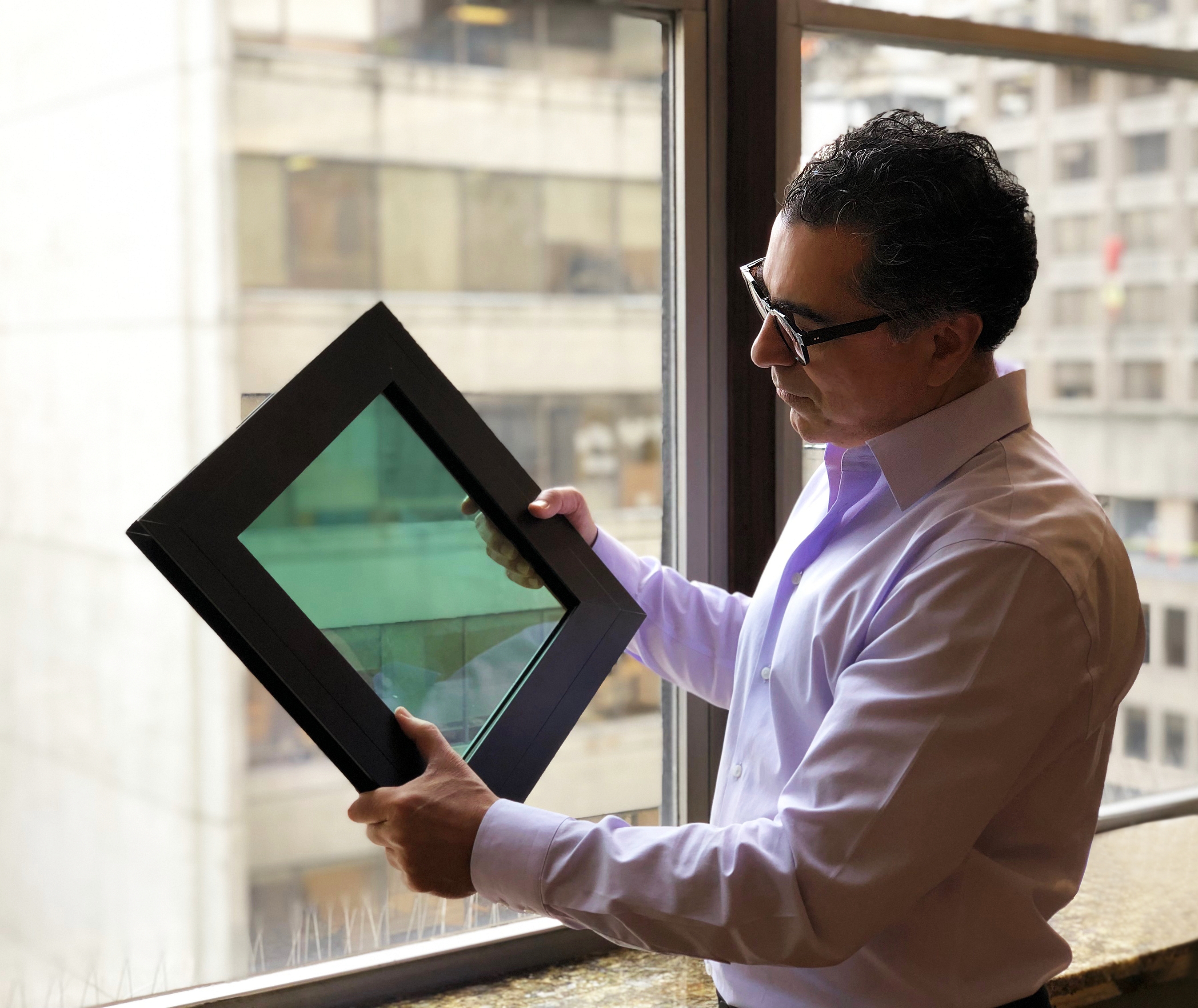 Harmel Rayat examining a SolarWindow module.