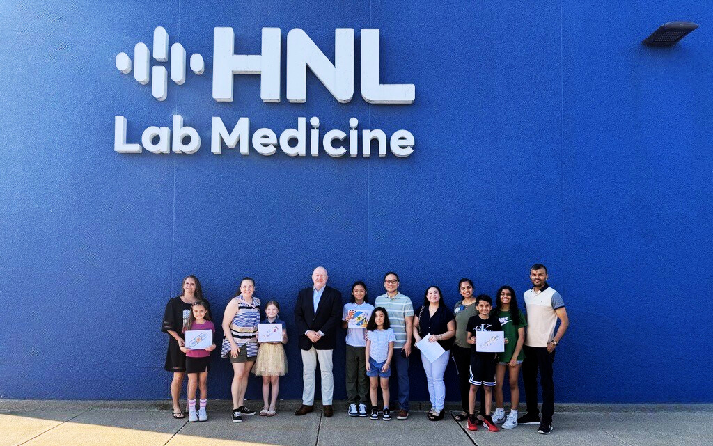 Art contest winners and their families pose in front of HNL Lab Medicine headquarters with CEO Martin K. Till.