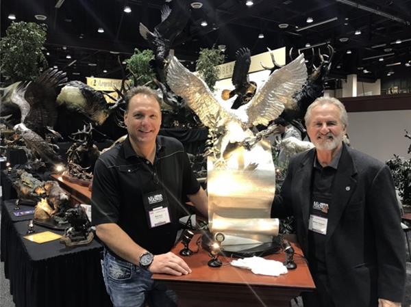 Foundry Michelangelo Founder, Mark Russo, and Director of Investor Relations, Michael Sheppard, stand proudly next to The 'Presidential' American Patriot Silver Edition sculpture in Treasure Investments Corp's MoneyShow booth