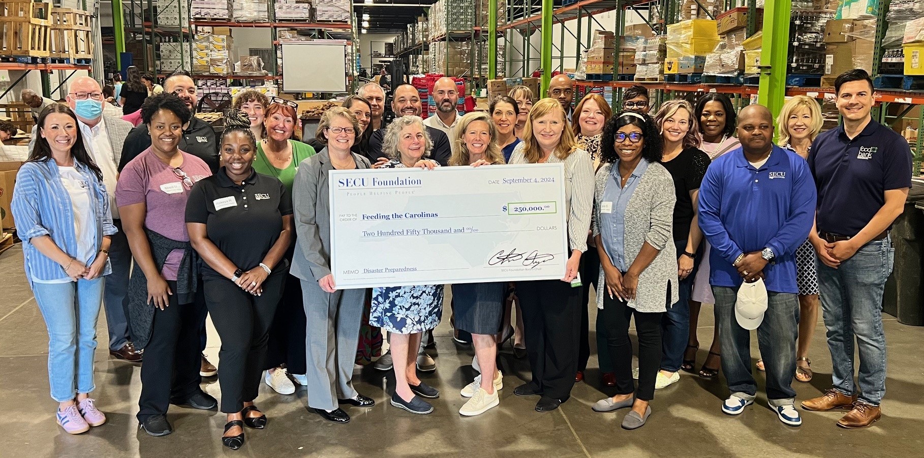 Holding check left to right are SECU Foundation Board members Mona Moon and Barbara Perkins; SECU Foundation Executive Director Jama Campbell; and Food Bank of Central and Eastern North Carolina Chief Development Officer Melissa Hartzell surrounded by local SECU branch leaders attending food bank volunteer event.