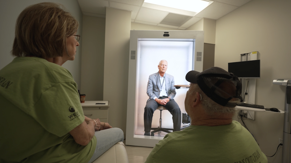 Using Proto Hologram's devices and spatial computing platform, Dr. Kurt Tauer. Medical Oncologist, Chairman and Co-Founder of West Cancer Center & Research Institute beams from the Memphis-area headquarters to its rural office in Paris, TN for visits with patients. One of the first patients to experience a hologram appointment said, “I’ve had dozens of virtual visits on my cell phone and this holographic experience doesn’t compare. It feels just like I am talking with my doctor face-to-face.” (Photo courtesy of West Cancer Center)