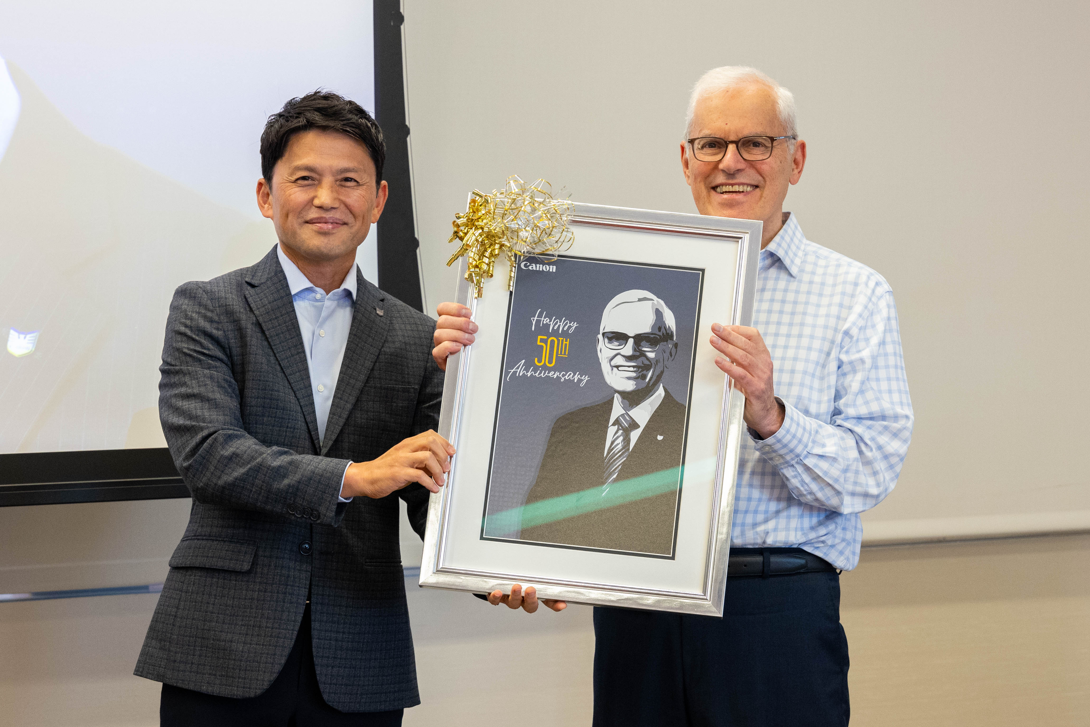 Canon U.S.A., Inc. President and CEO Isao “Sammy” Kobayashi congratulates Executive Vice President Seymour Liebman on 50th work anniversary.