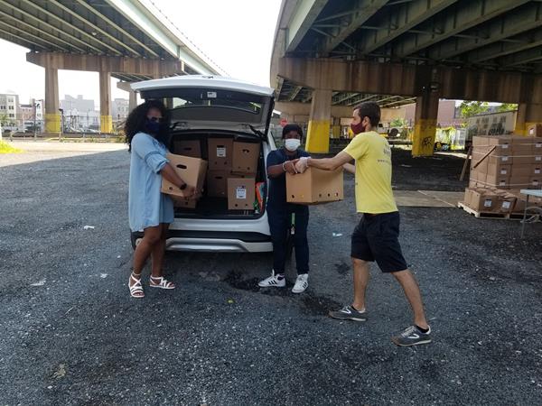 Daniel Torrance of Liberty Resources (right) hands boxes of fresh produce to Rashera Sharpe (left) and Karimah Cannon (center), both of Patterson Transportation, a LogistiCare transportation provider responsible for delivering food to Philadelphia residents with disabilities in need. 