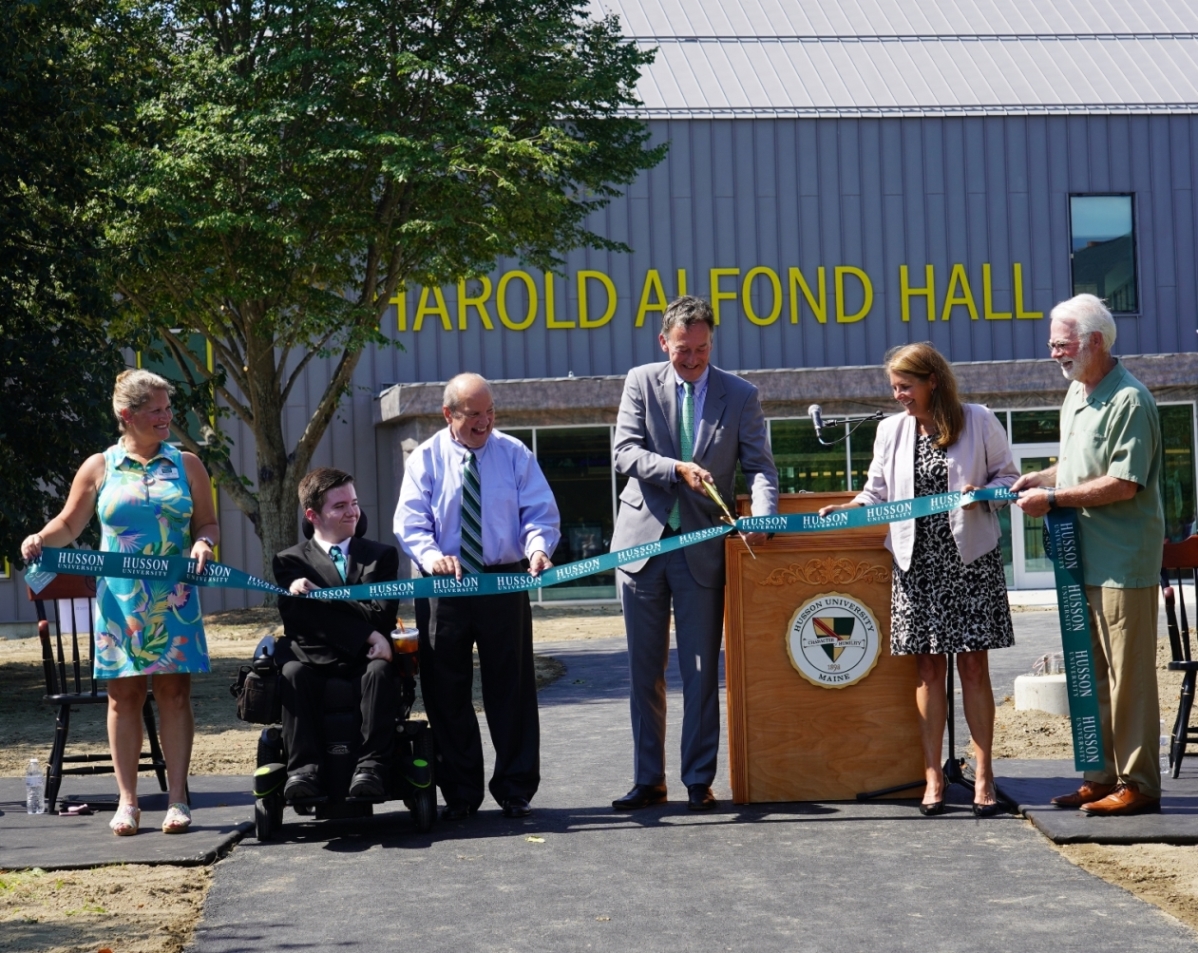 Helping to cut the ribbon for Harold Alfond Hall, the new home of Husson University’s College of Business were (from left to right) Marie Hansen, JD, PhD, SHRM-SCP, dean of the College of Business and New England School of Communications (NESCom); Tyler Smith, a student pursuing a Bachelor of Science in Integrated Technology with a concentration in web design and development from the College of Business’s School of Technology and Innovation; Robert A. Clark, PhD, CFA, president of Husson University; Greg Powell, chief executive officer and president of Dexter Enterprises, Inc. and chair of the Harold Alfond Foundation’s Board of Trustees; Commissioner Heather Johnson from the Maine Department of Economic Community Development; and John M. Rohman, the retired CEO of WBRC Architects / Engineers of Bangor and chair of Husson University’s Board of Trustees.