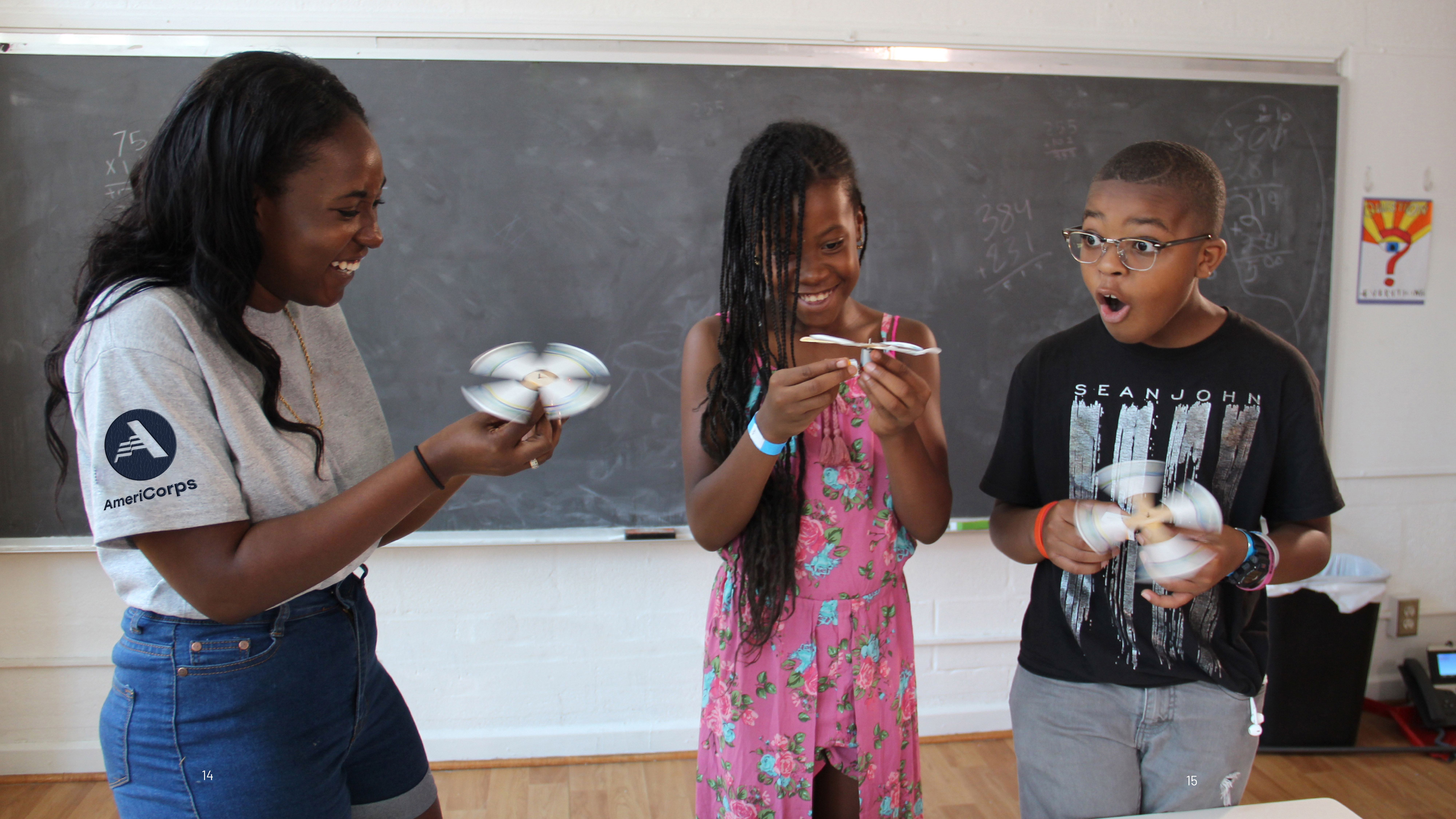 An AmeriCorps member demonstrates a STEM project in a classroom to two surprised students. 