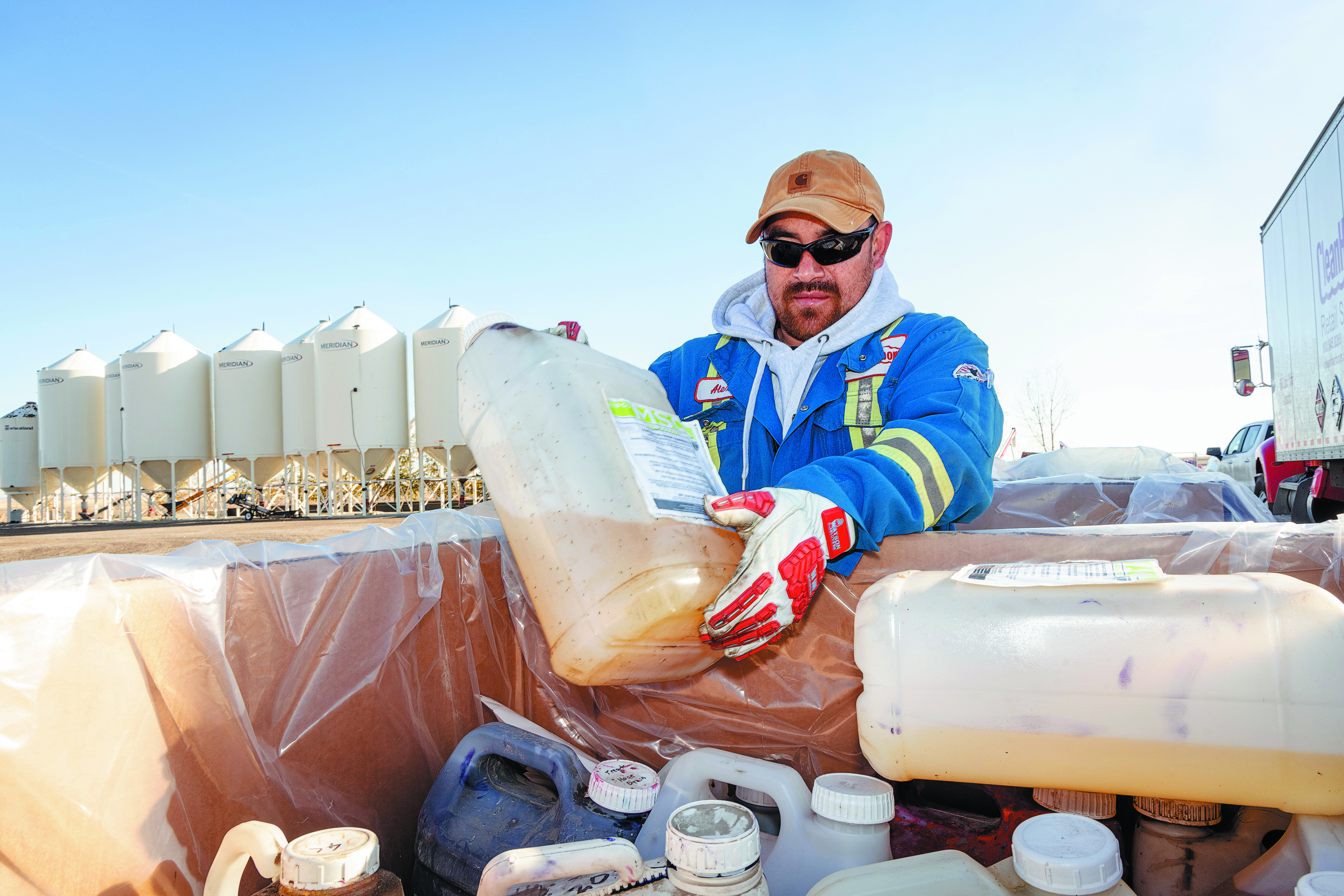 Trained collection representative safely handling containers of unwanted agricultural pesticides and obsolete livestock medications at a drop-off.