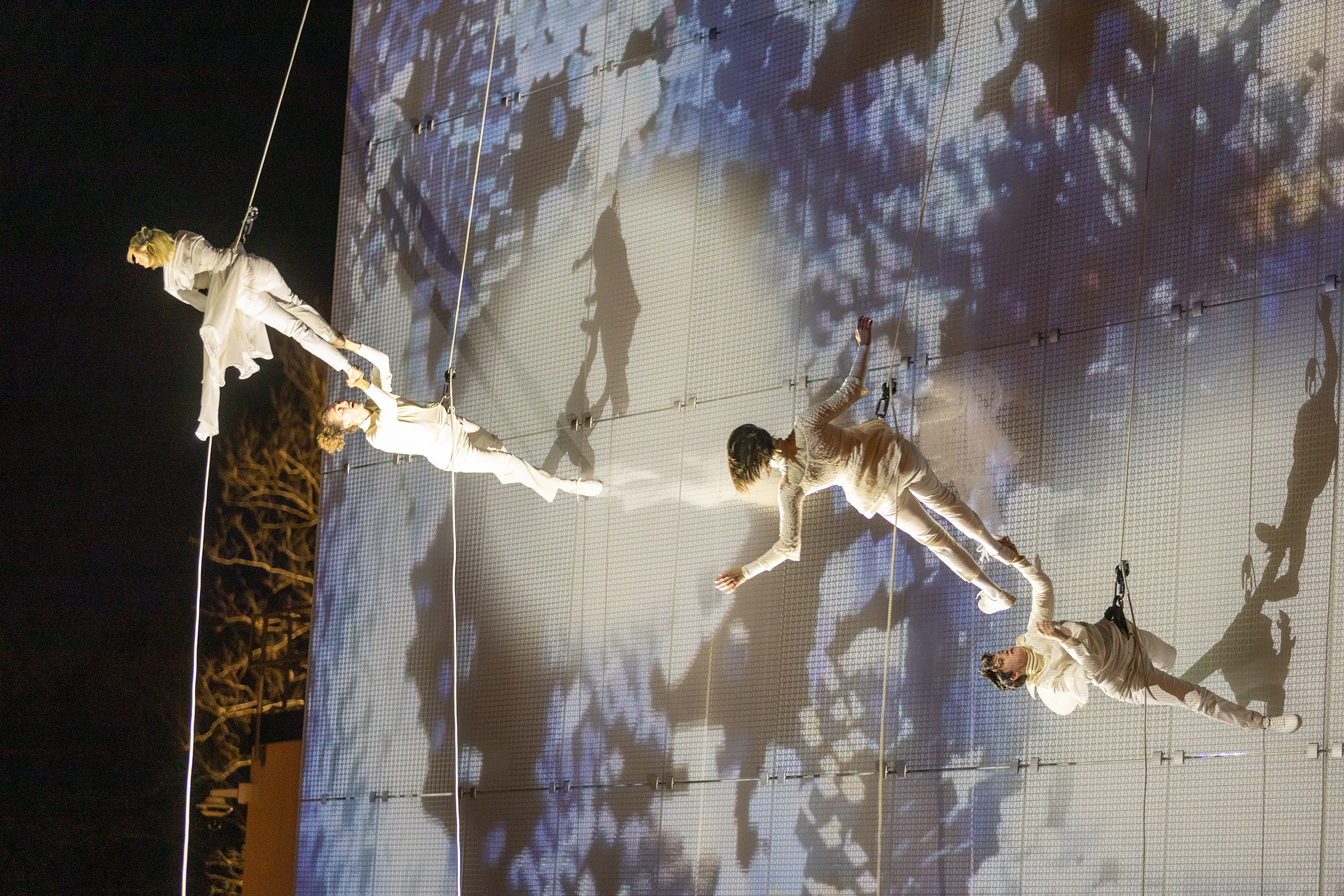 The opening night at The Momentary museum was celebrated with an enigmatic dance on top of the Bendheim projectable glass facade. Photo courtesy of BANDALOOP. 