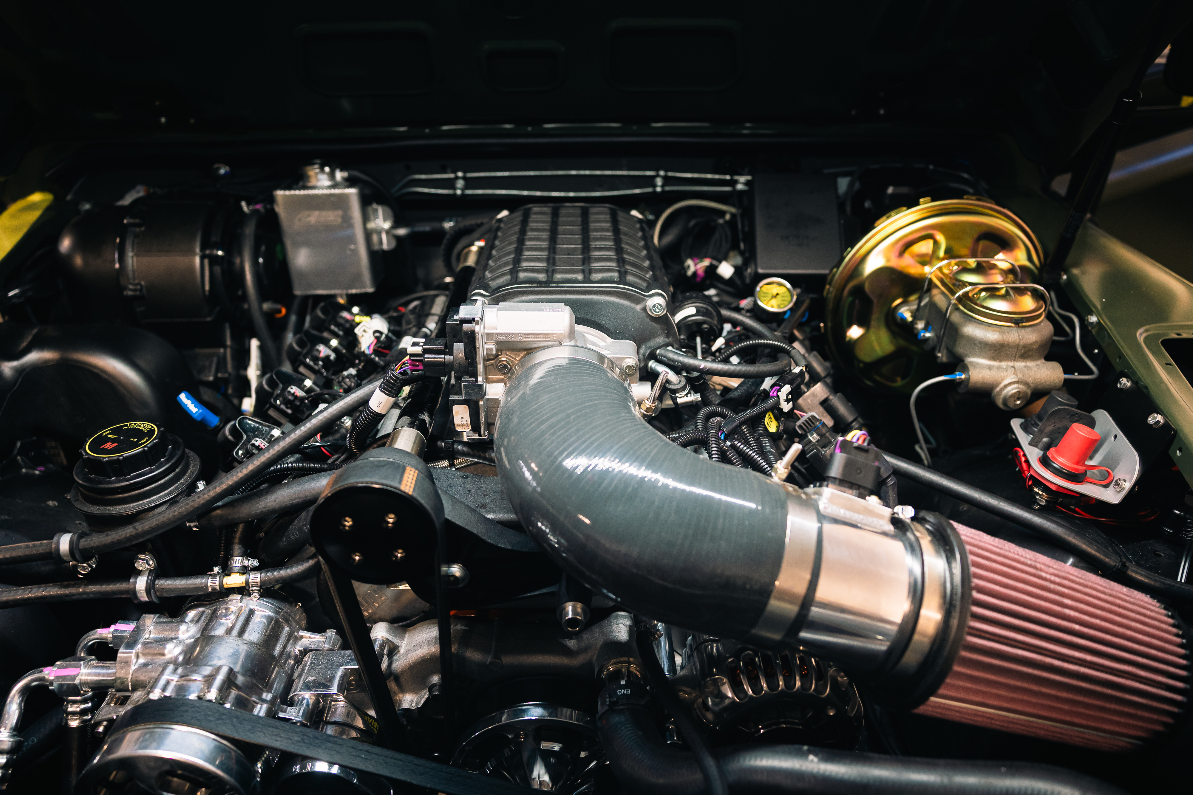 Close-up view of ECD 's 700+HP BLUEPRINT V8 engine installed in a custom Defender, featuring supercharger assembly and performance intake system 
