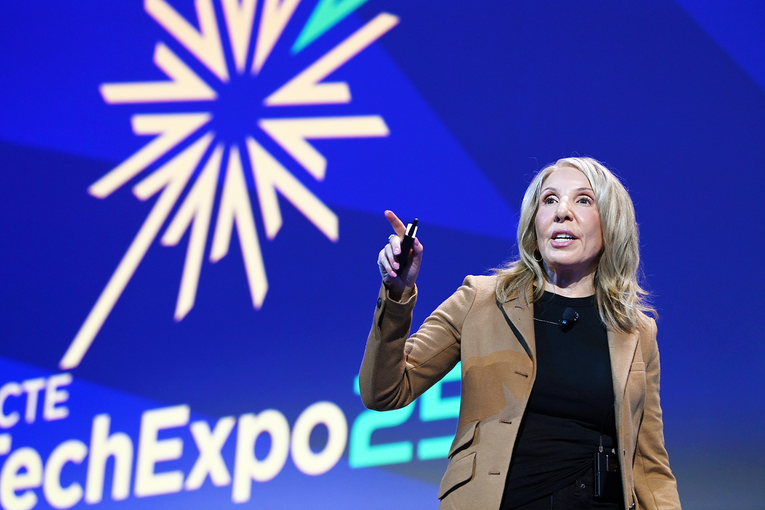 Maria Popo speaking on stage at TechExpo25, with SCTE TechExpo25 logo in the background.