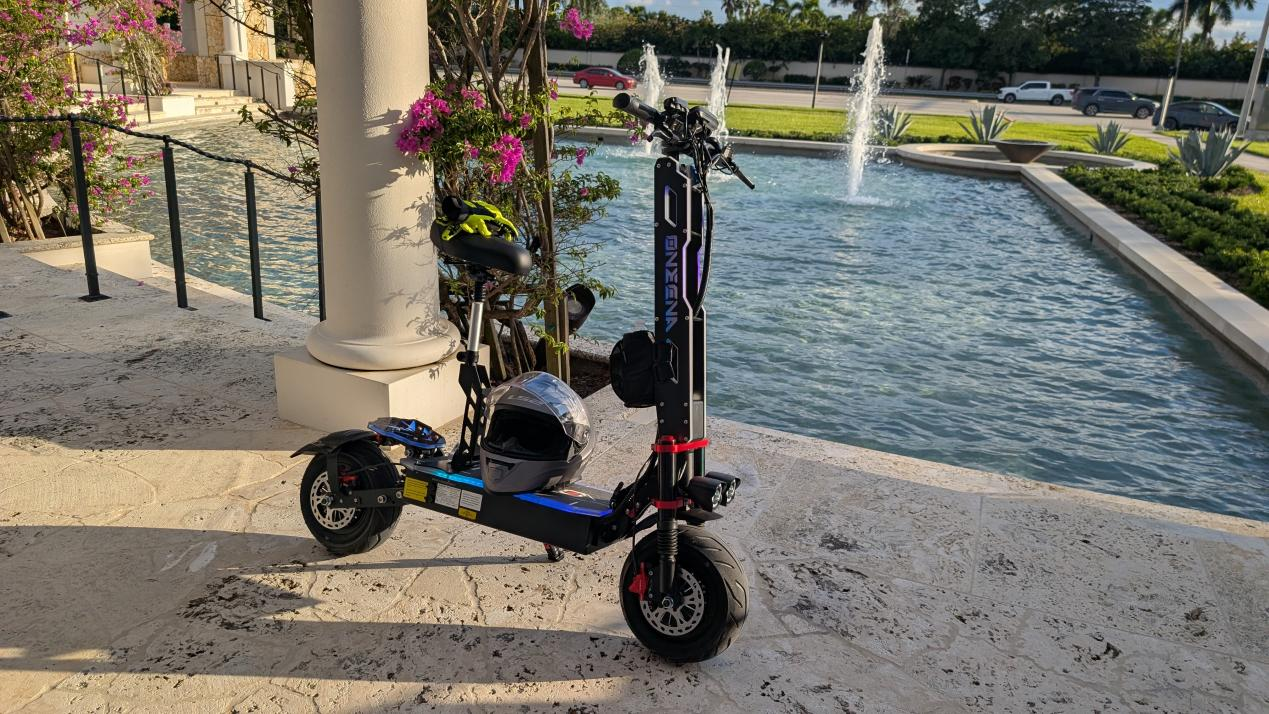 A sleek ONECNA GT9 electric scooter rests near a fountain, helmet on its platform.