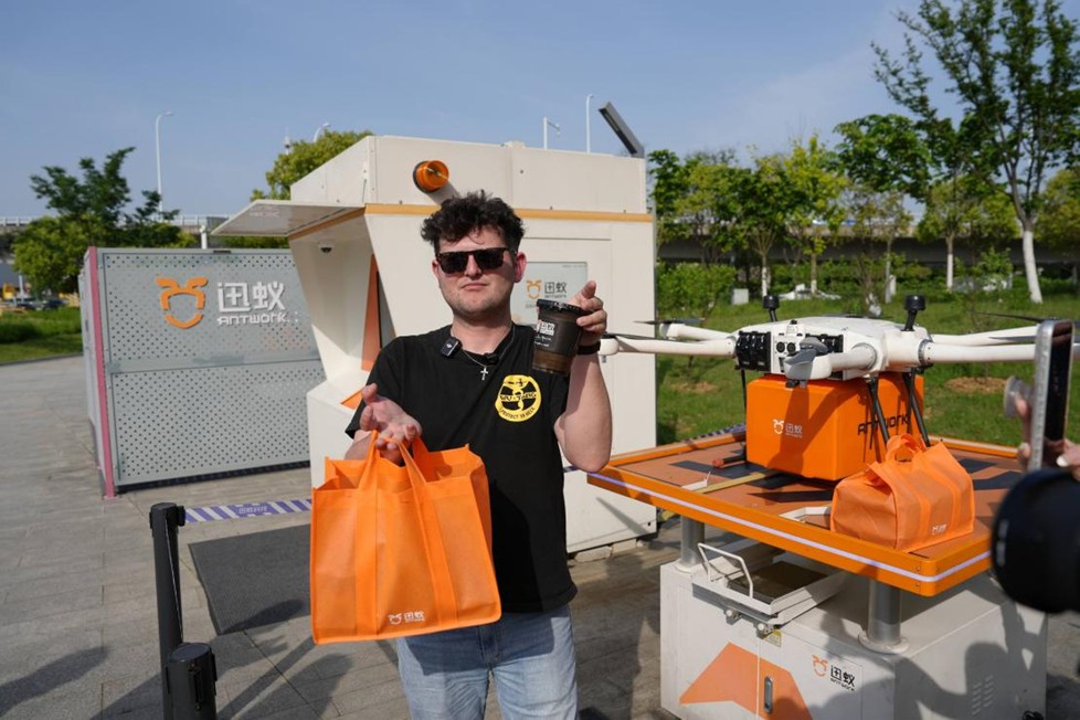 Content creator Joe Burns proudly shows off his coffee, freshly delivered by a drone, in Hefei. [Photo provided to chinadaily.com.cn]