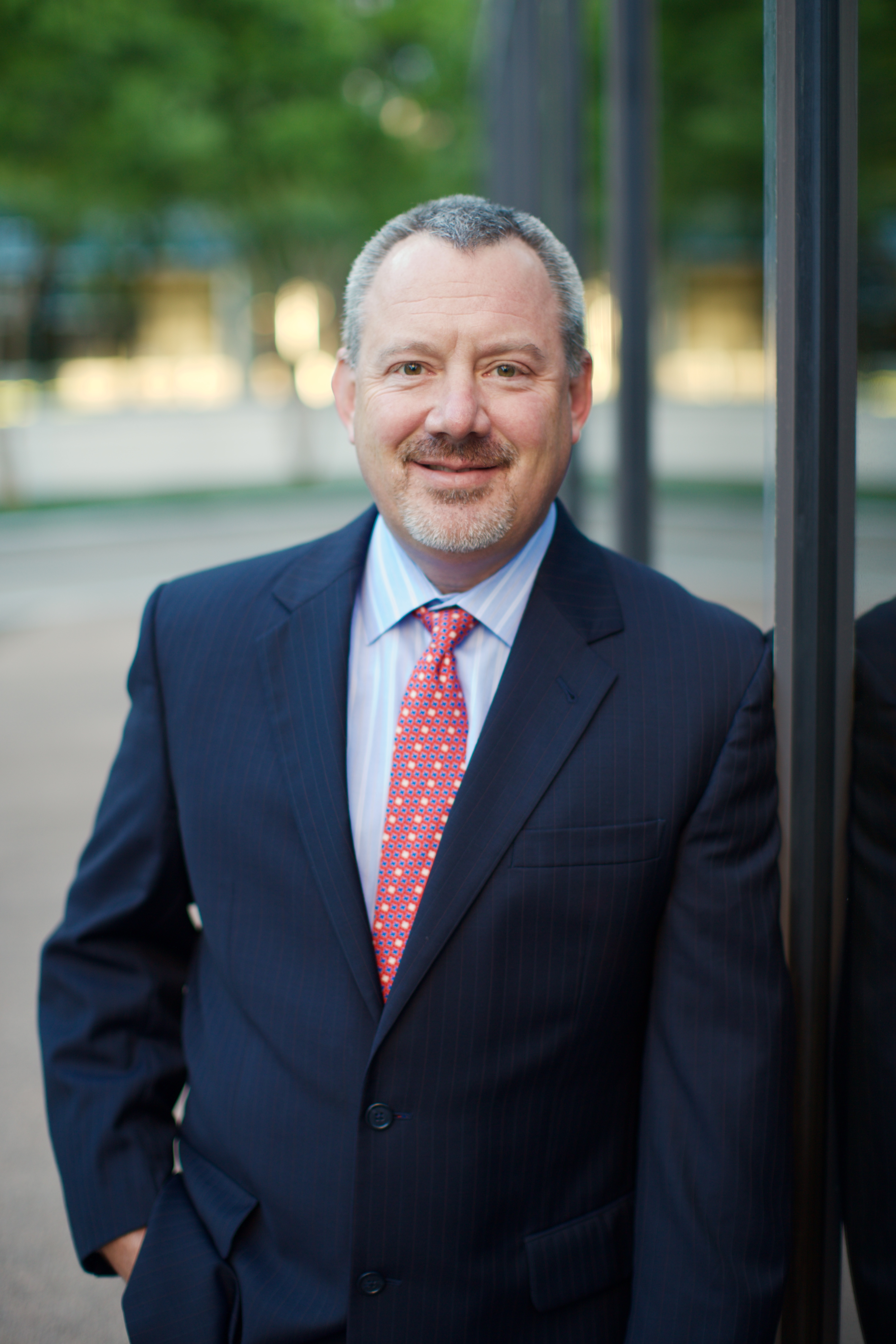 Kip Wright, Chief Executive Officer of The Planet Group, wearing a navy suit and red tie in a professional headshot.