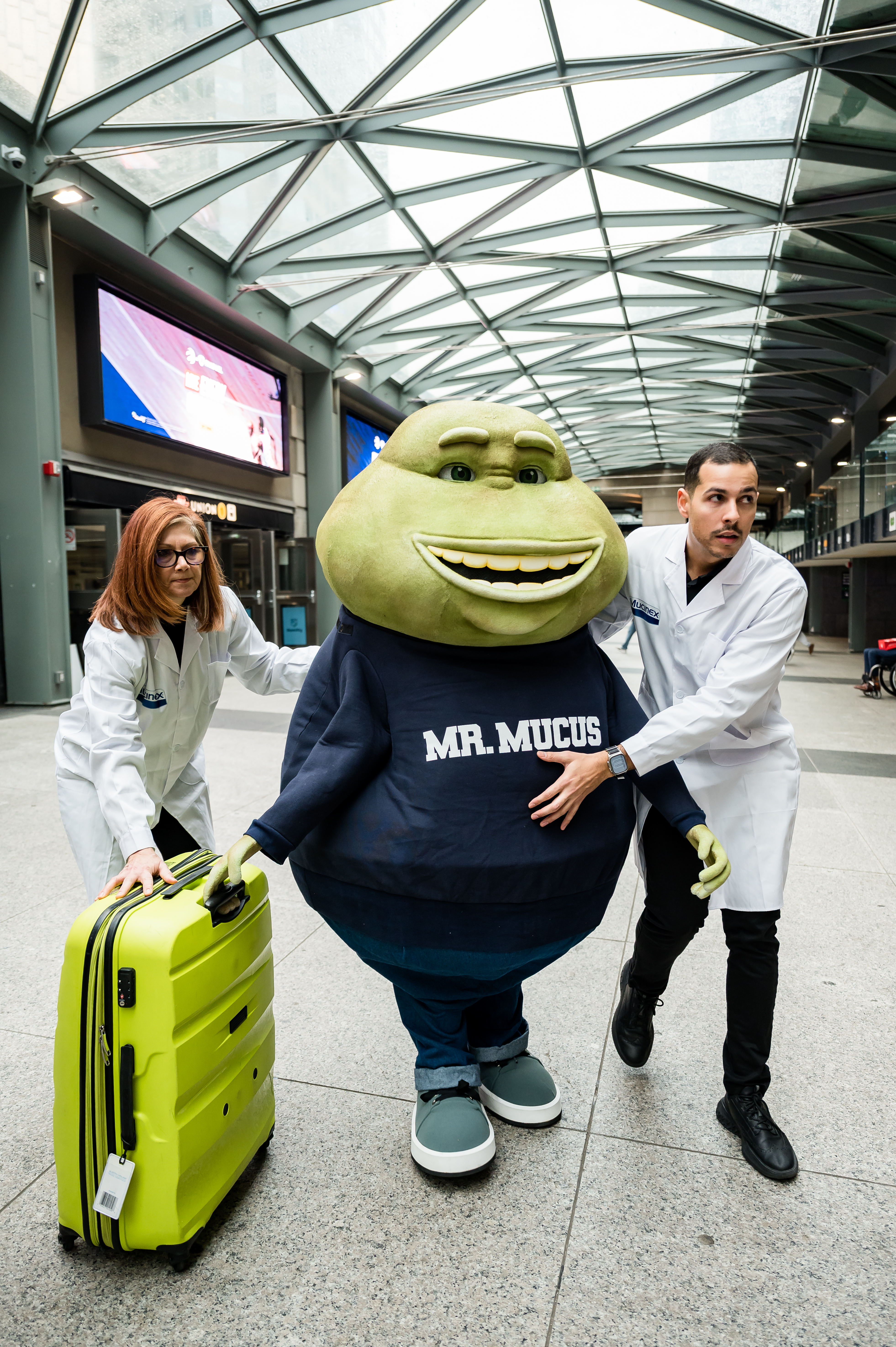 Mr. Mucus is escorted out of the train station by the Mucus Relief Crew