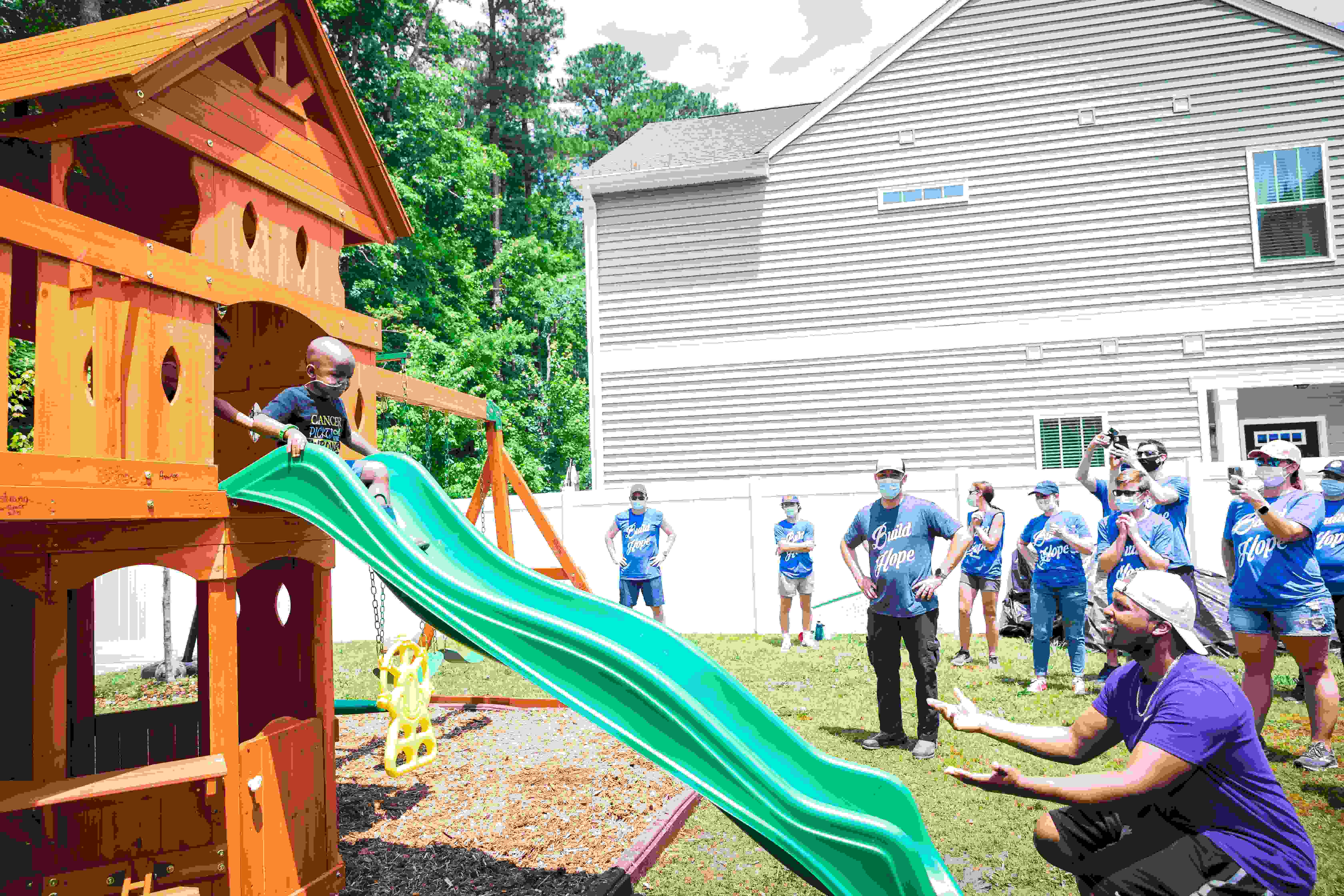 Five-year-old Cayden Addison, who is fighting Leukemia, tests out his new playset as he slides to his dad Darryl Addison as volunteers of the Roc Solid Foundation look on. Cayden's playset was donated and built by the non-profit organization, whose mission is to build hope for thousands of families fighting pediatric cancer by providing playsets and distributing ‘Ready Bags’ to hospitals all across the country.