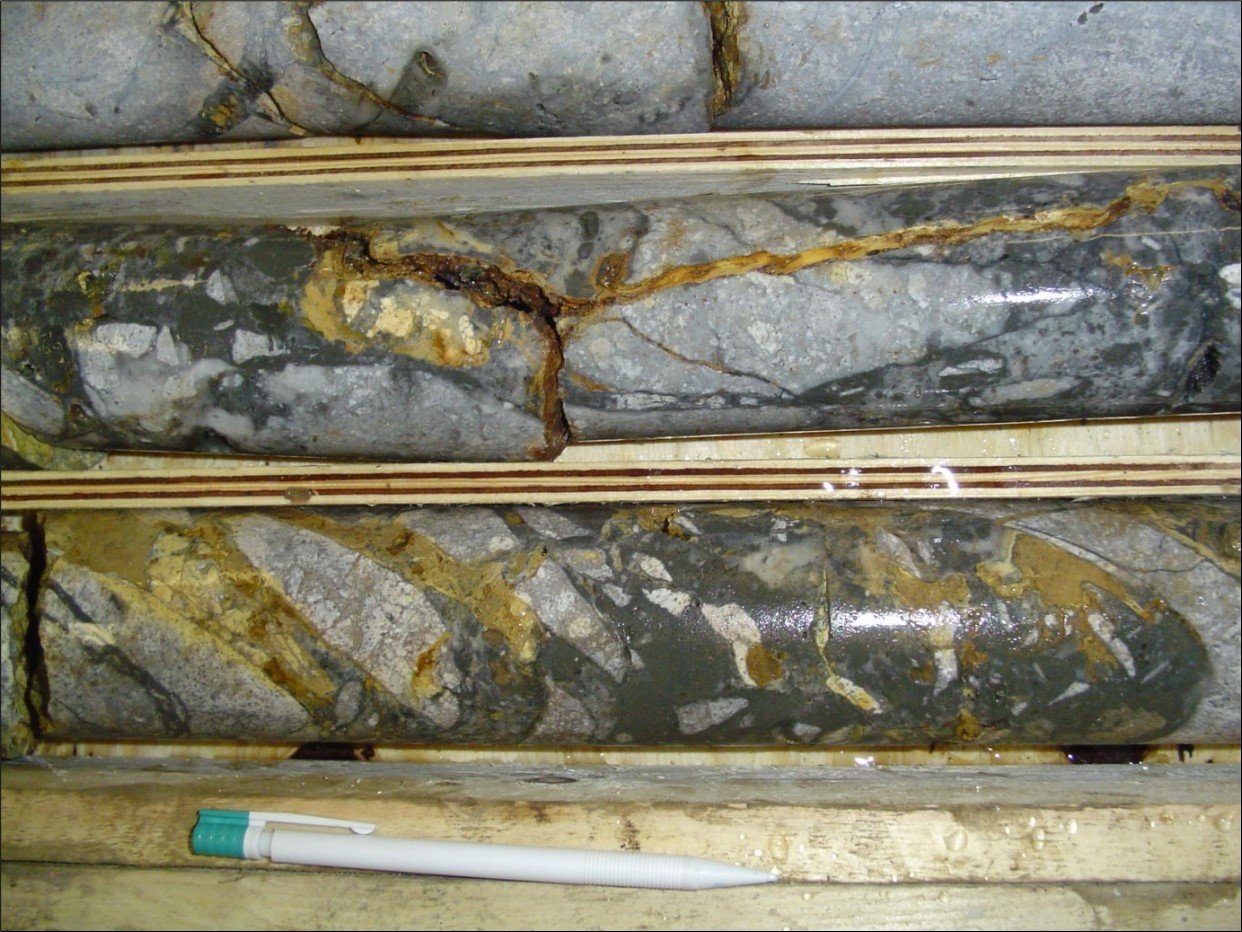 Strongly silicified rhyolite tuff, brecciated, with dark chalcedony and stibnite stockwork infill plus limonite (orange) after sulfides (KG-BL-1: 104.1-105.5m; 2.98g/t Au)