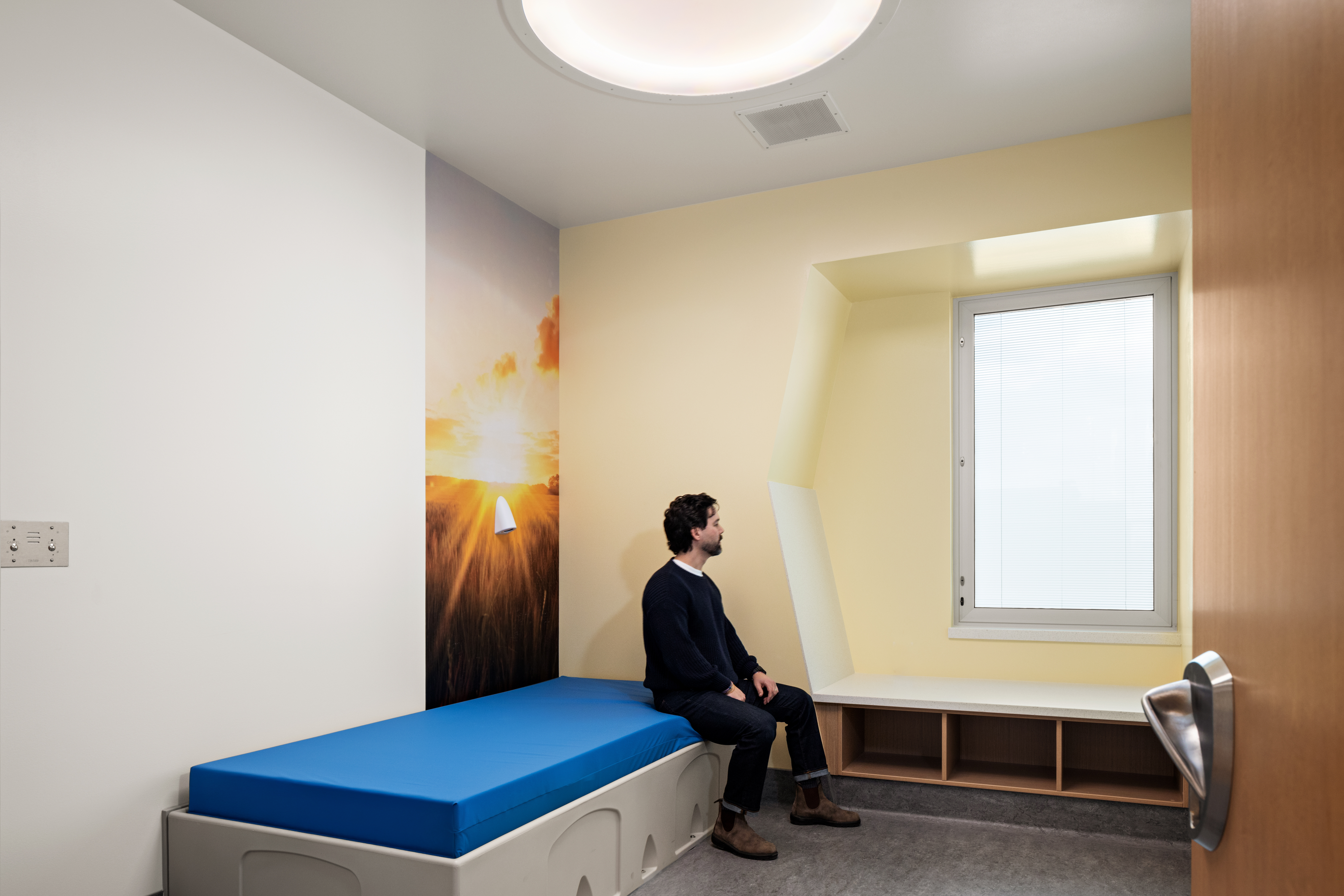 Private room at Columbia Valley Center for Recovery with a padded bed, wall mural and built-in window seat.