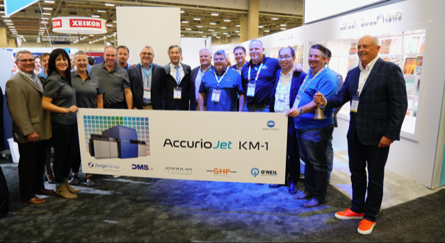 Oct. 23, 2019,  – Dallas, TX – Customers celebrated purchases of Konica Minolta’s AccurioJet KM-1 LED UV Inkjet Press at PRINTING United. (L-R) T. Bentley, Dir., Bus. Development, Ind. Print, Konica Minolta; B. Stainbrook, VP, Ind. Print, Konica Minolta; N. Jenkins, Bus. Development Dir., American Printing; T. Gulbransen, VP, Sales & Marketing, American Printing; V. Kapalczynski, President & CEO, American Printing; J. Kleven, Supply Mgr., American Printing; S. Zenger, President, Zenger Group; K. Sugie, Exec. Officer Ind. Print & Production Print, Konica Minolta, Inc; J. Zenger, CFO, Zenger Group; J. Zenger, VP, Zenger Group; B. Forrester, Dir., Bus. Development, Ind. Print, Konica Minolta; M. Robinson, VP, Summit Direct Mail; T. Uemura, Gen. Mgr., Ind. Print, Konica Minolta, Inc; J. Barber, CEO, Summit Direct Mail; R. James, Dir., Bus. Development, Ind. Print, Konica Minolta; B. Troxil, Sr. VP, Strategic Bus. Development, Konica Minolta