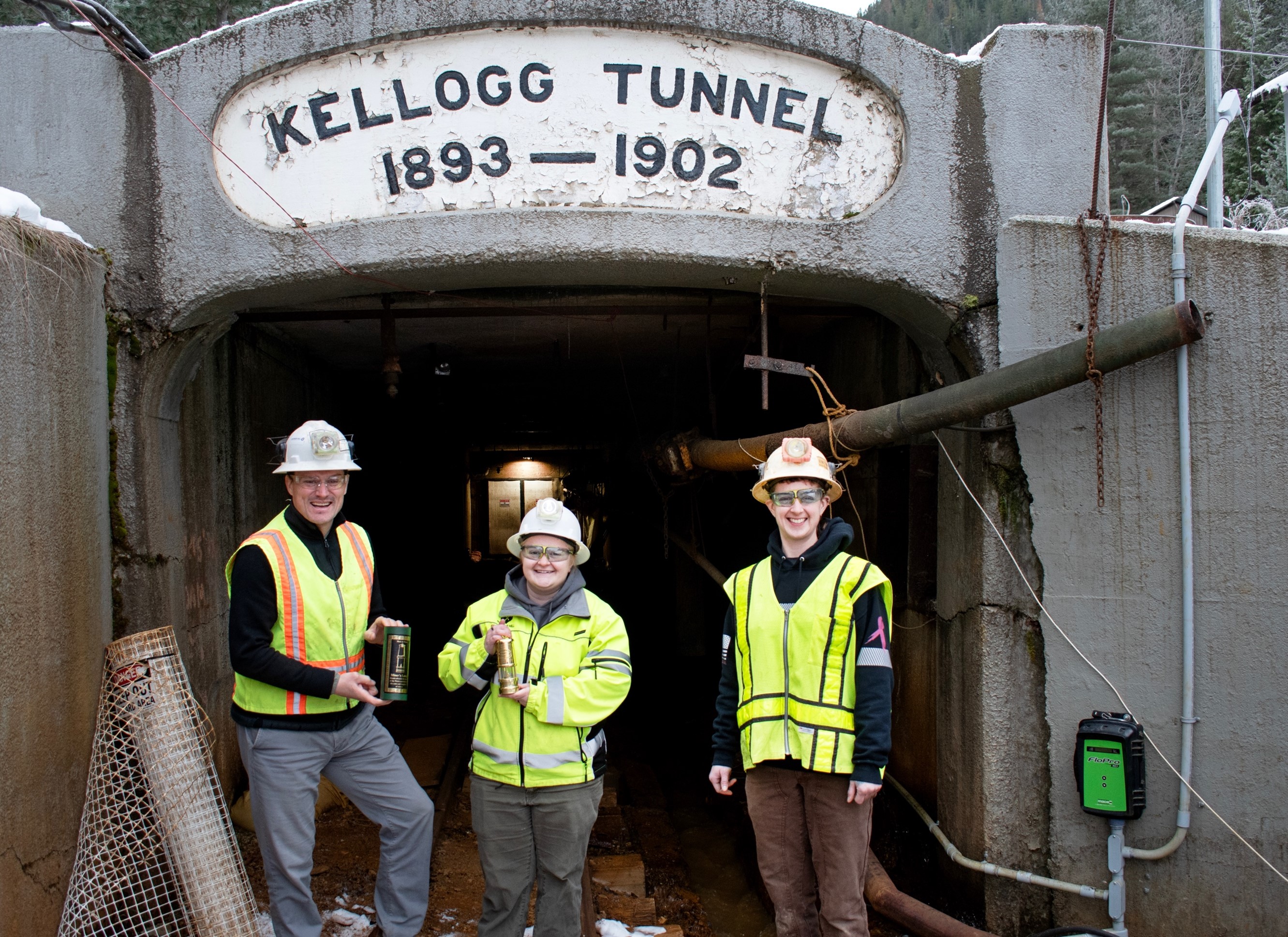Bunker Hill’s General Manager Tom Francis, Environmental Manager Morgan Hill and Survey Technician Karen Ryan holding the award next to the water discharge monitoring station in the Kellogg Tunnel entrance.