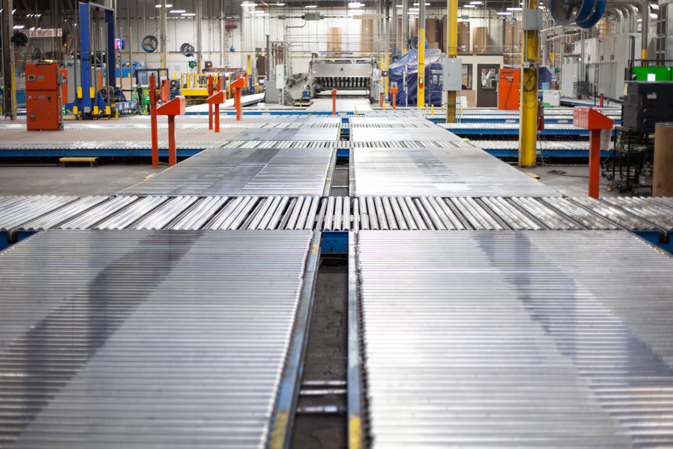 Long automated roller conveyor lines transporting corrugated sheets through President Container Group's sustainable cardboard box manufacturing facili