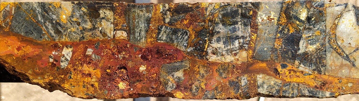 High-grade oxide gold mineralisation at SFdLA: Tourmaline-sericite altered siltstone clasts supported in a weathered and gossanous goethite-hematite matrix (after chalcopyrite-tourmaline). SFDH-034, 27.4m. From a 1m sample that averaged 59.1 g/t gold, 295 g/t silver and 0.07 % copper. Photograph is of a selected interval and is not necessarily representative of mineralisation hosted throughout the property.