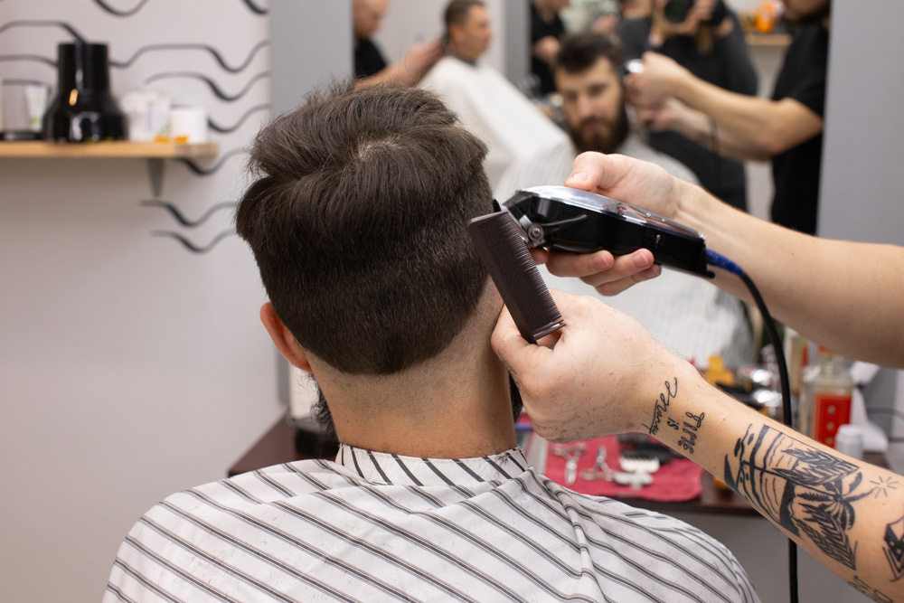 Barbering professional giving his male client a hair cut