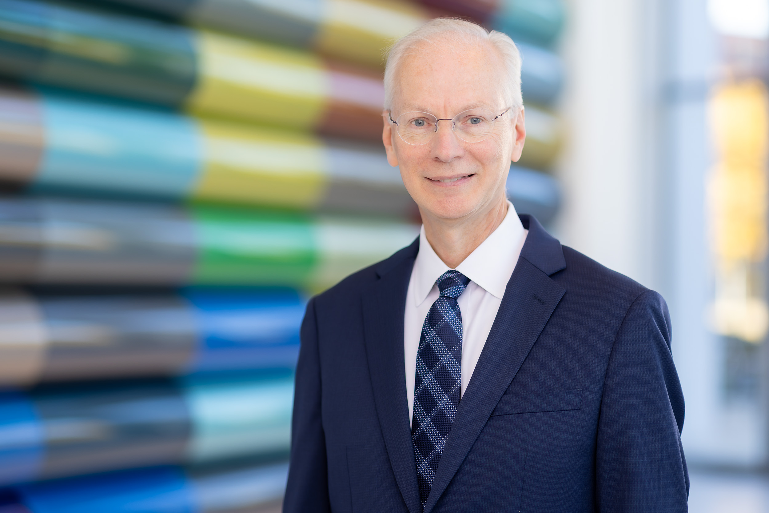 Image of Dr. Robert K. Roop standing in front of a wall with colored panels 