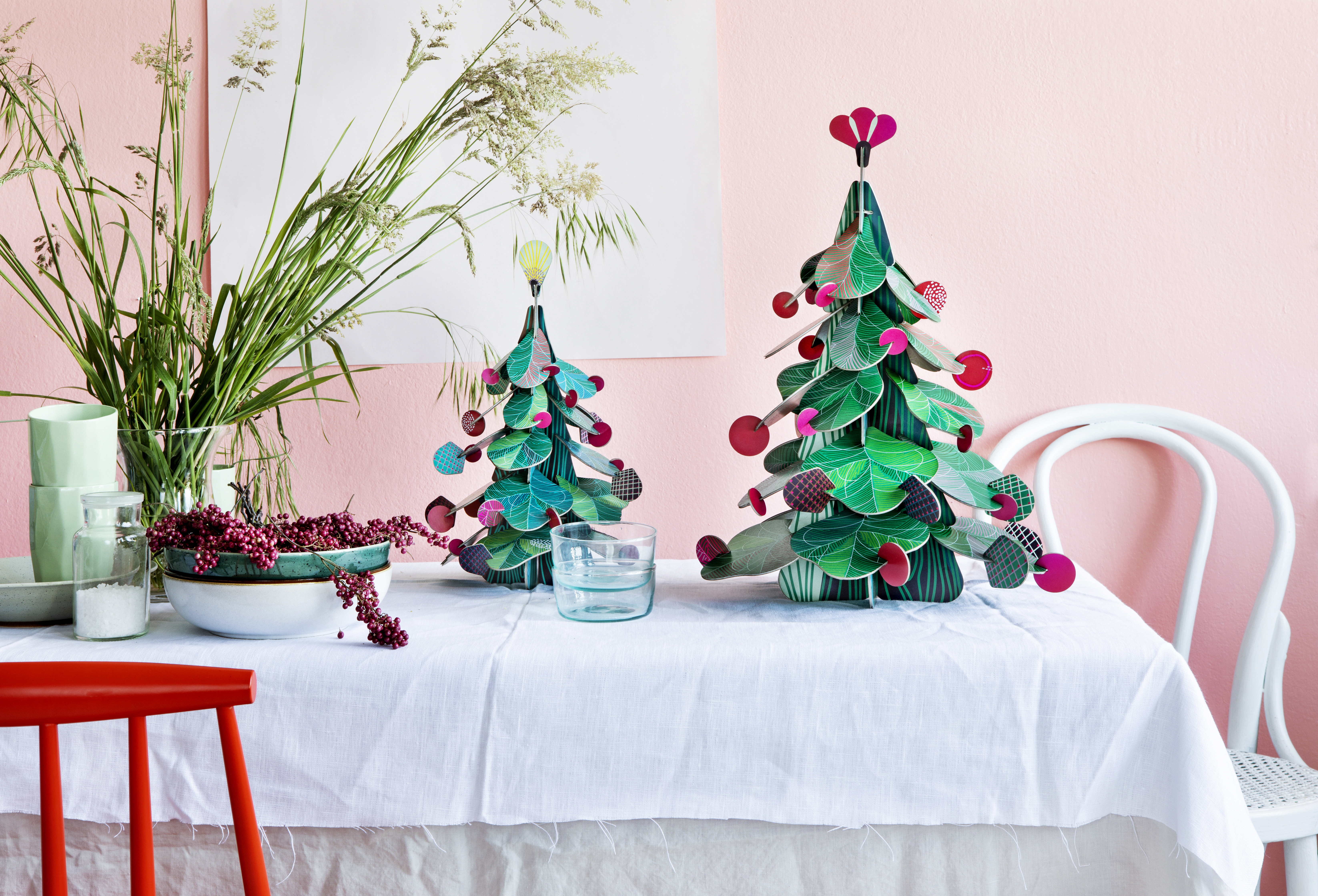 Arbres de Noël 3D en carton Studio ROOF présentés sur une table festive aux couleurs vives avec accessoires décoratifs dans un décor lumineux de Nüspa