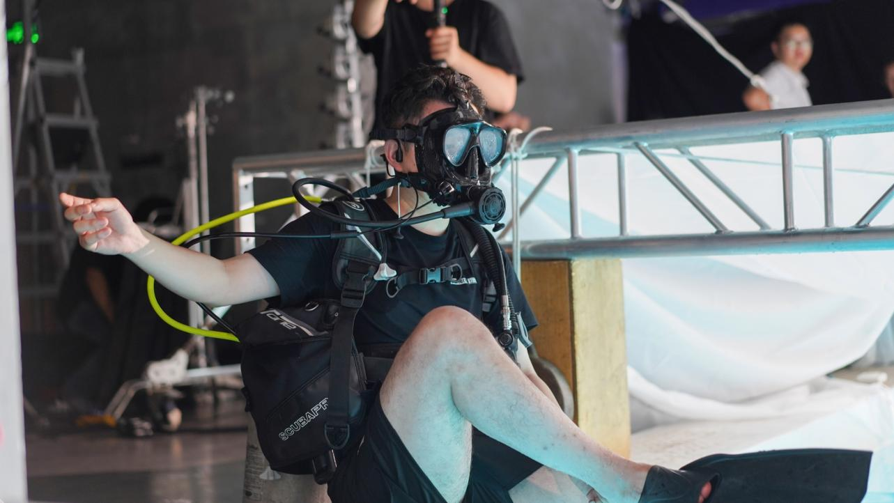 An underwater camera operator prepares beside the pool during the Starlight Luggage production