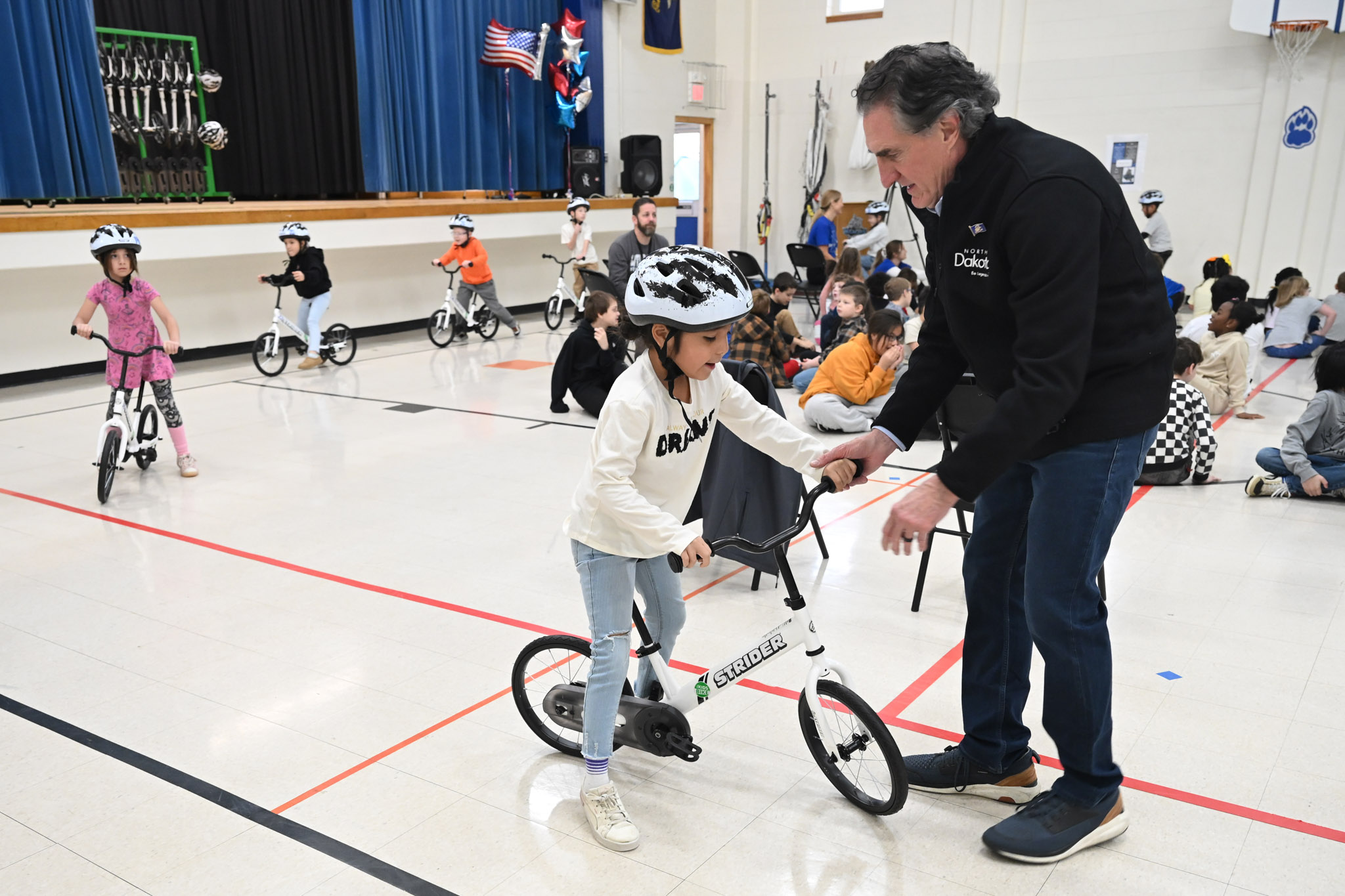 Governor Burgum helps a student with their bike at Will Moore Elementary School.