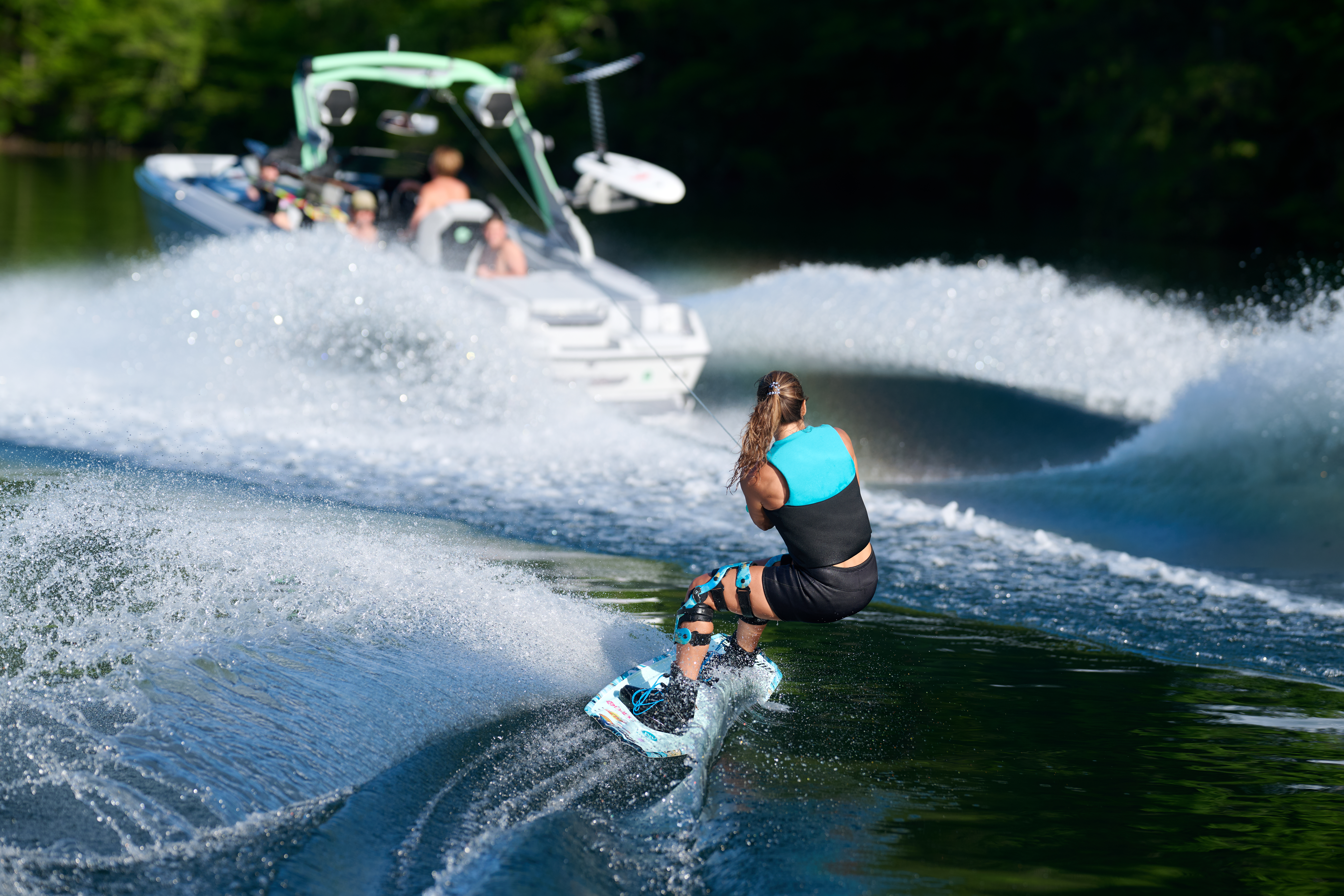 A rider launches off the wave behind the all-new 22 LSV as friends cheer from the boat, showcasing Malibu’s legendary wake performance.