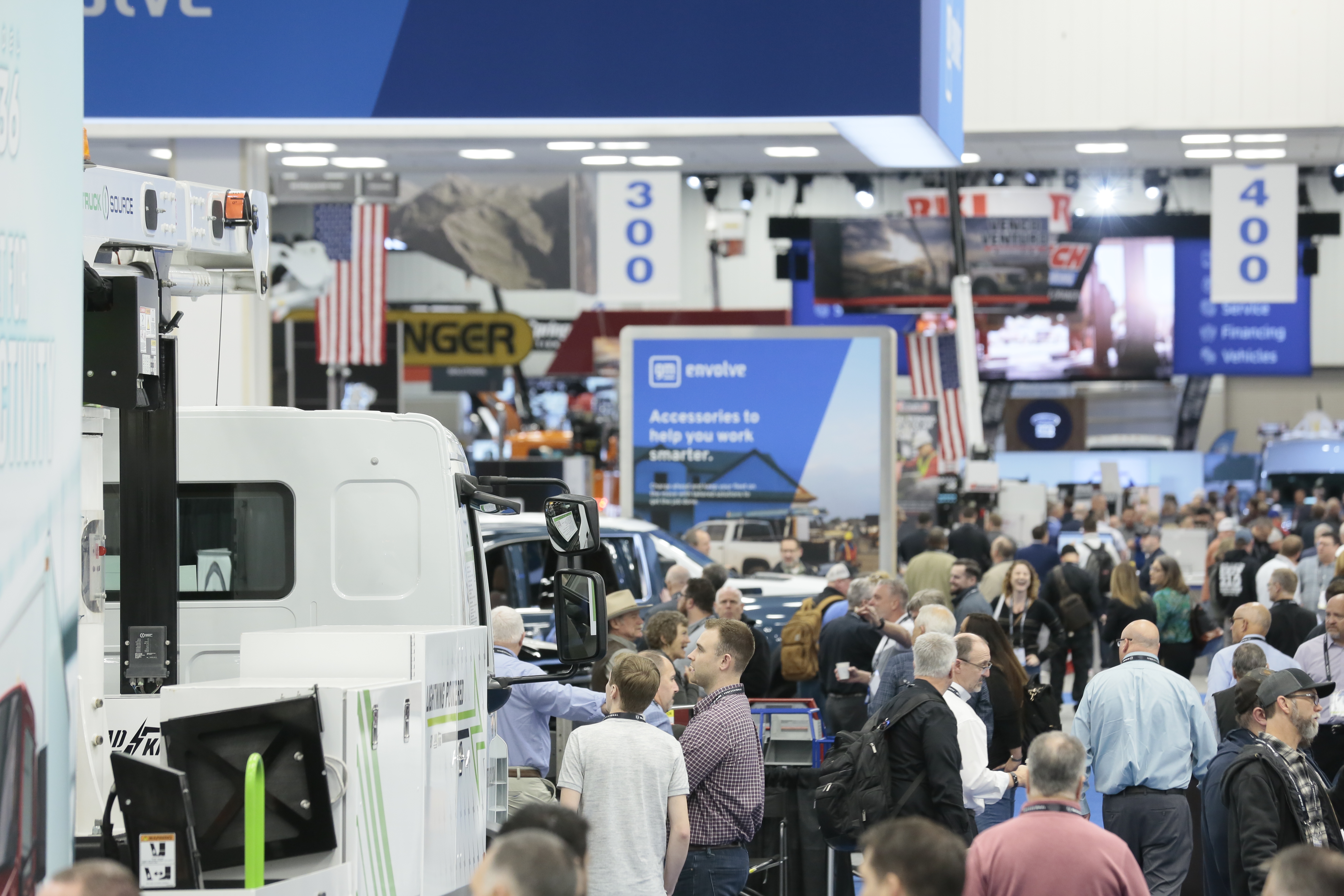 Photo showing a crowd of people walking around a show floor of trucks