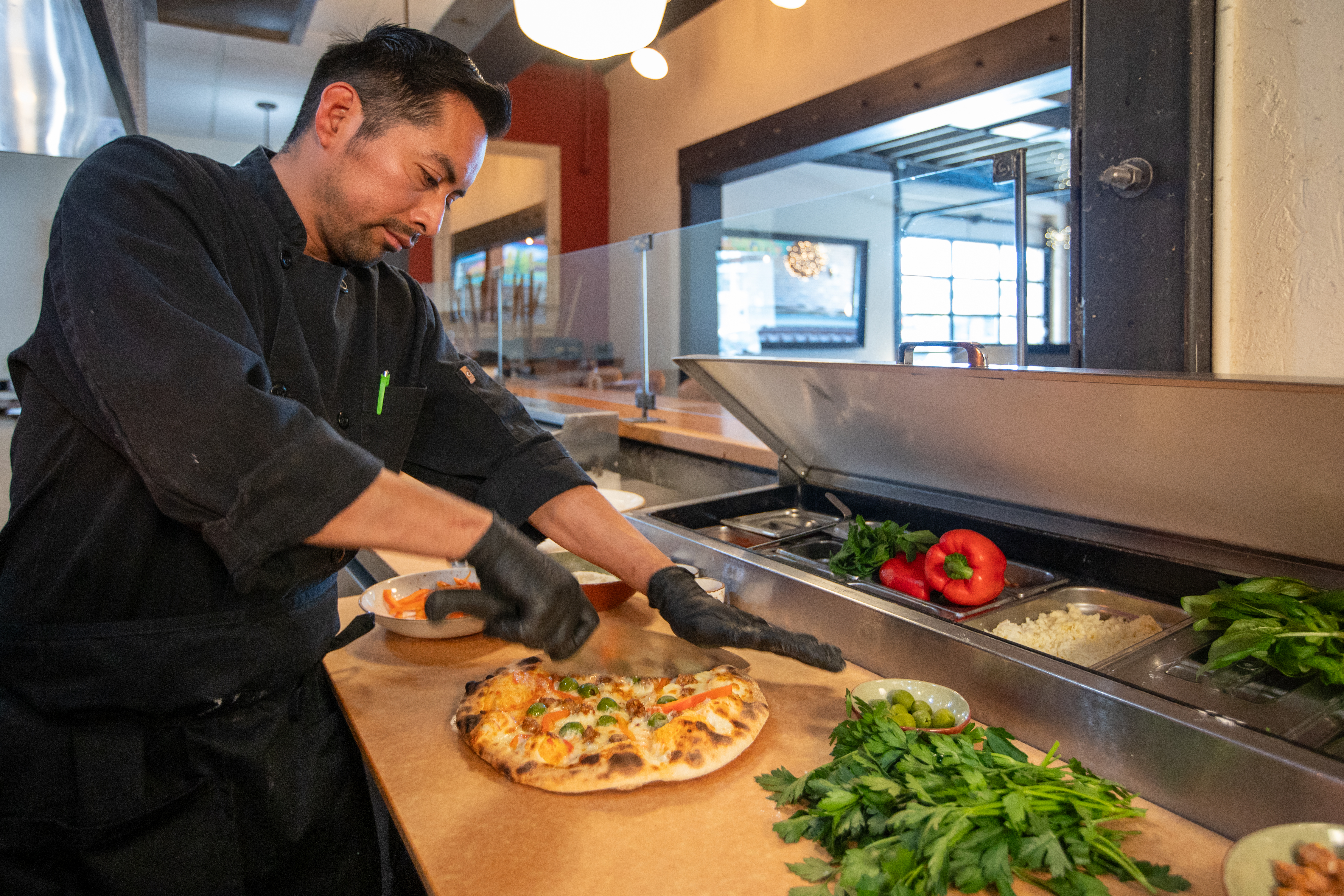 Man cutting pizza on a Richlite culinary surface.